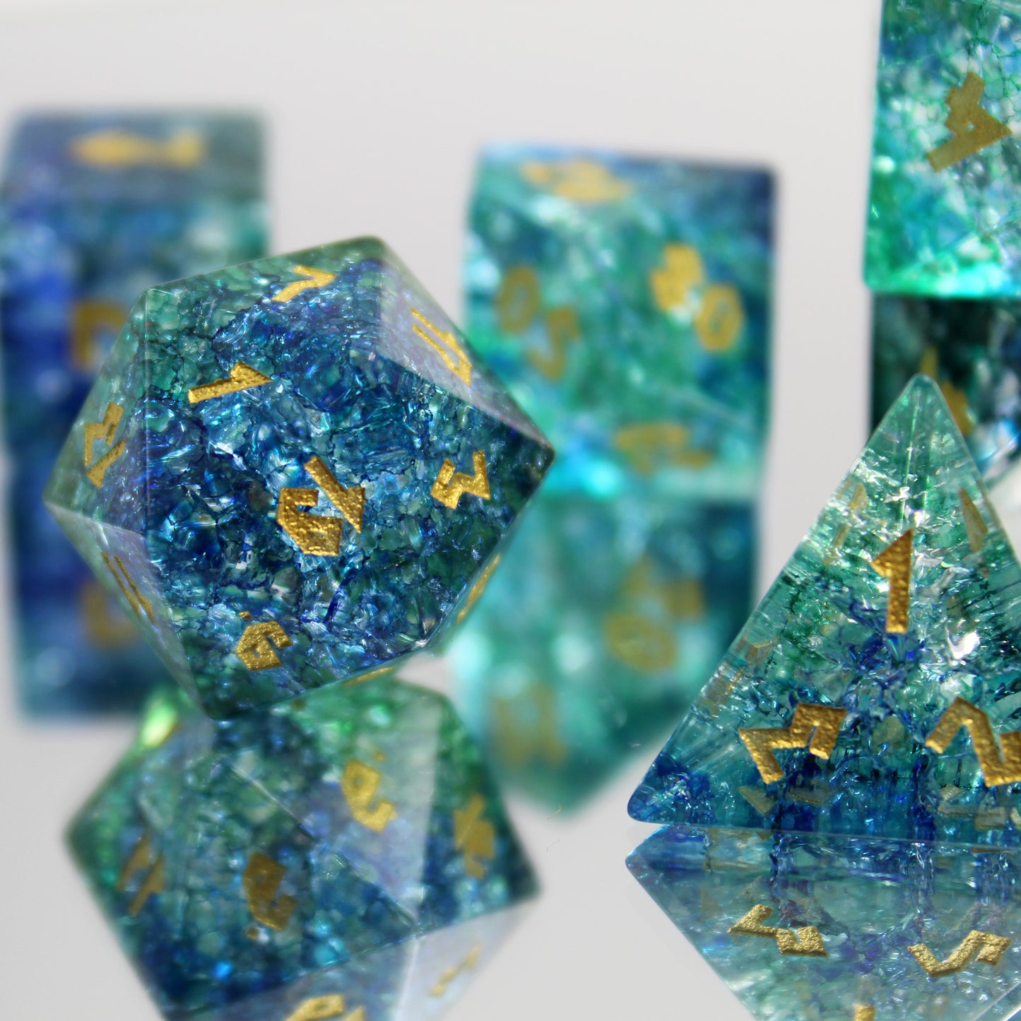 Set on a mirror with D20 in focus, showing gold-colored numbers on the Arctic Wave Shattered Glass Dice for RPG games.