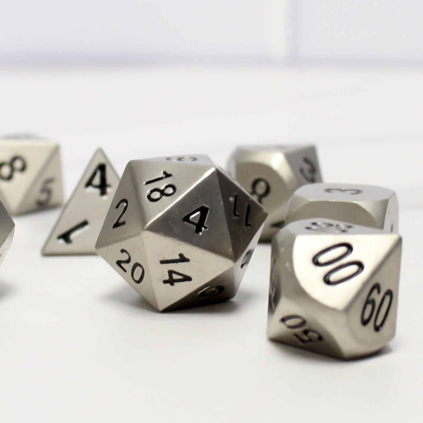Close-up of the bright silver dice set on a white background. The close-up showcases the bright silver faces and black numbering.