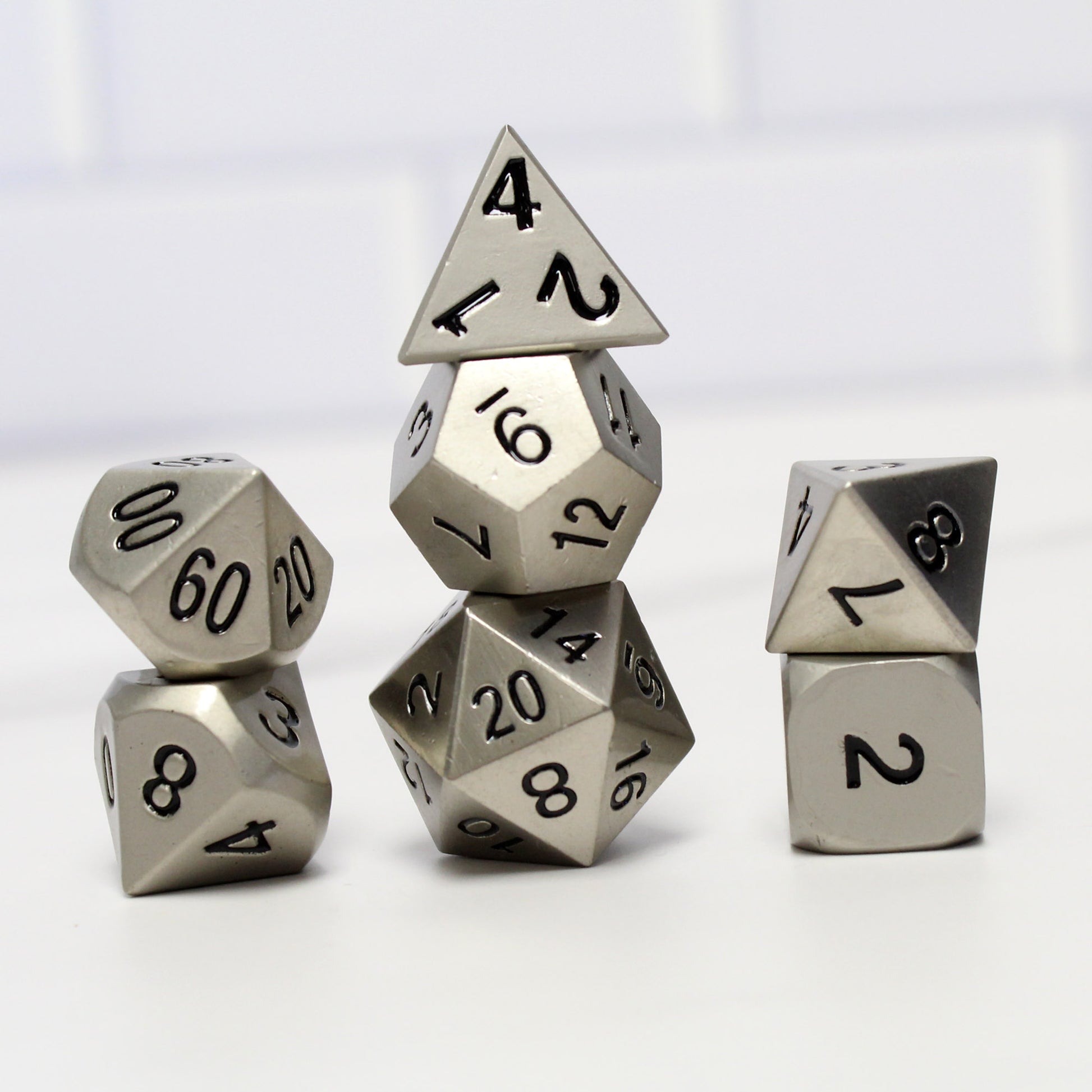 Bright silver dice set arranged in three stacks on a white background