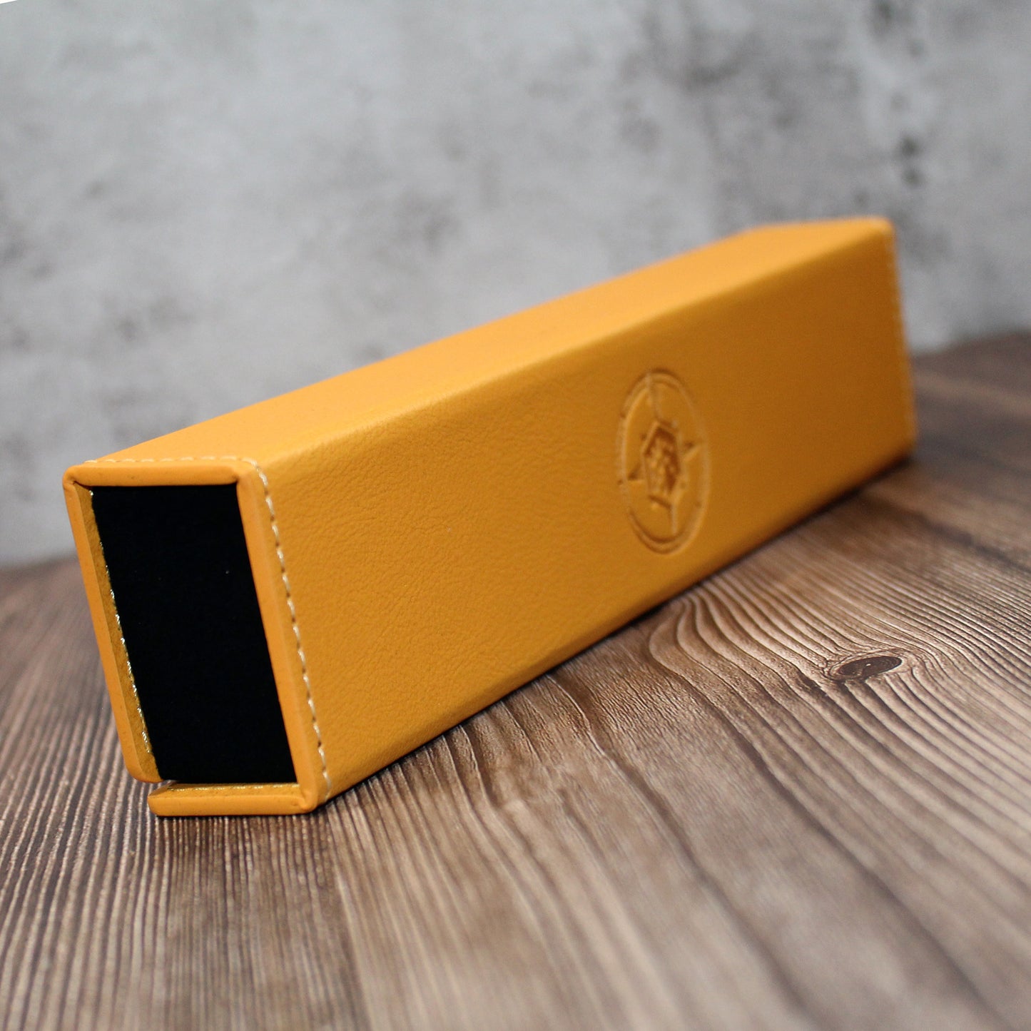 Yellow leather dice case with a Dice Dungeons logo on a wooden surface