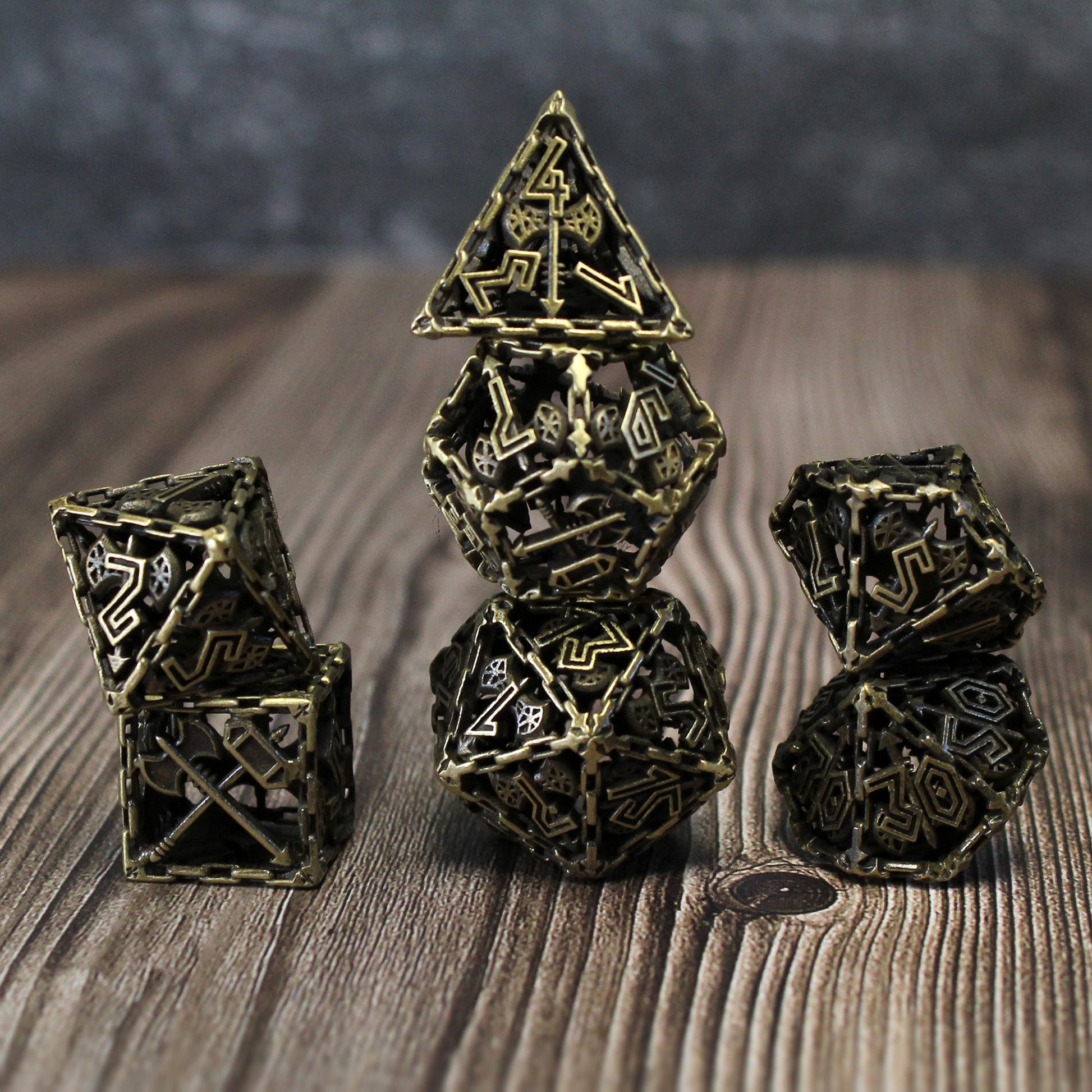 Bronze Barbarian Cage Dice Set stacked on a table, showcasing the hollow cage design with numbers superimposed on a double-headed axe and chain-bordered faces.