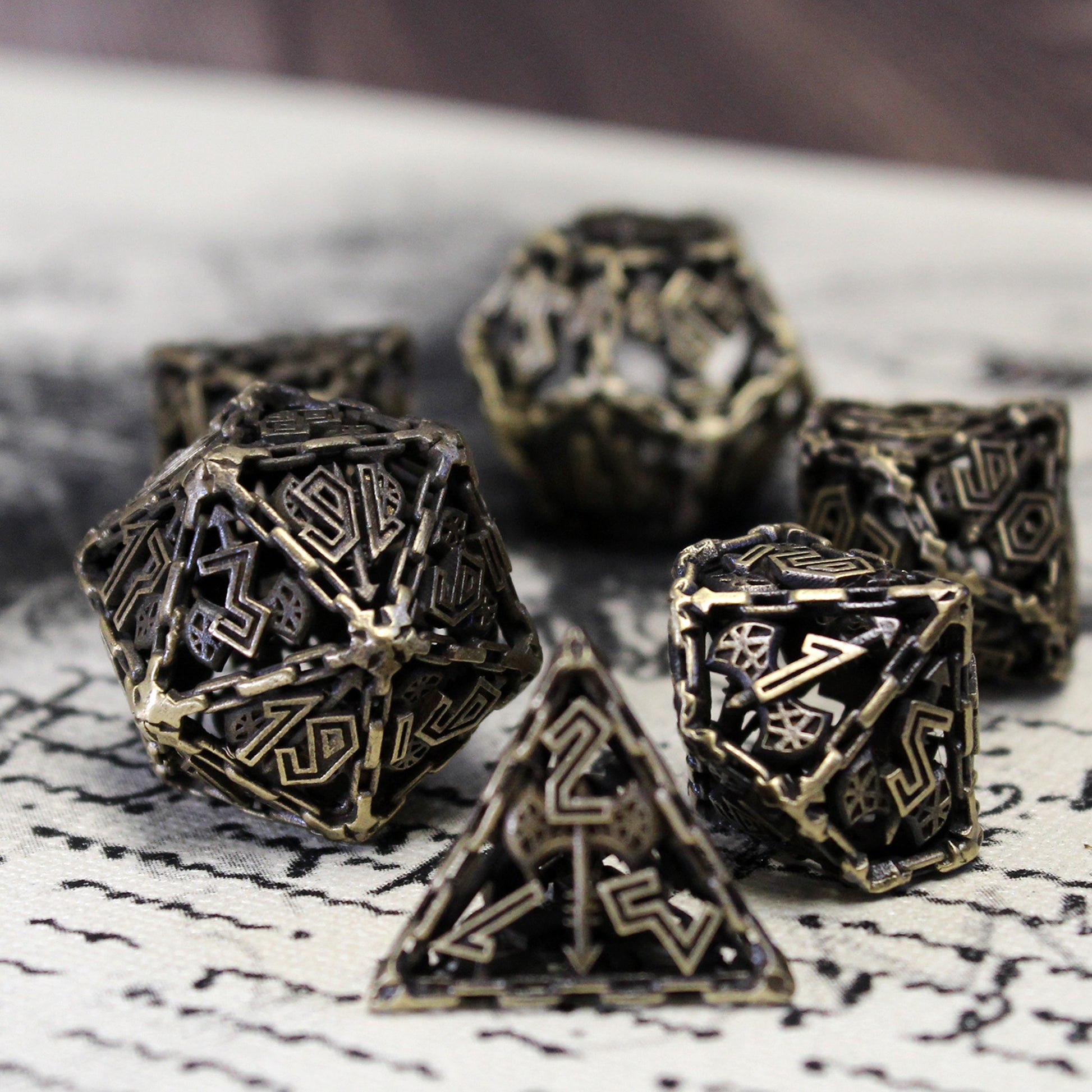 Full Barbarian Cage Dice Set displayed on an ancient text, highlighting the class-specific electro-plated brass design and battle-hardened aesthetic.