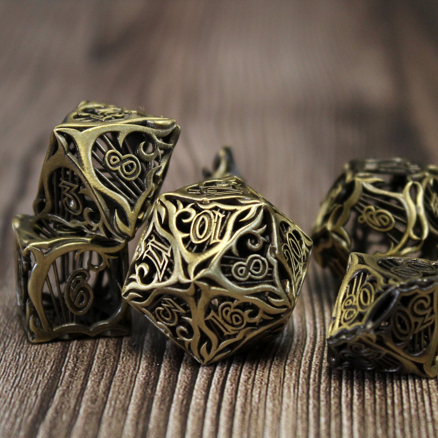 Set of seven bronze bard-inspired hollow metal dice with uninked numbers and harp motifs on each face on a wooden background