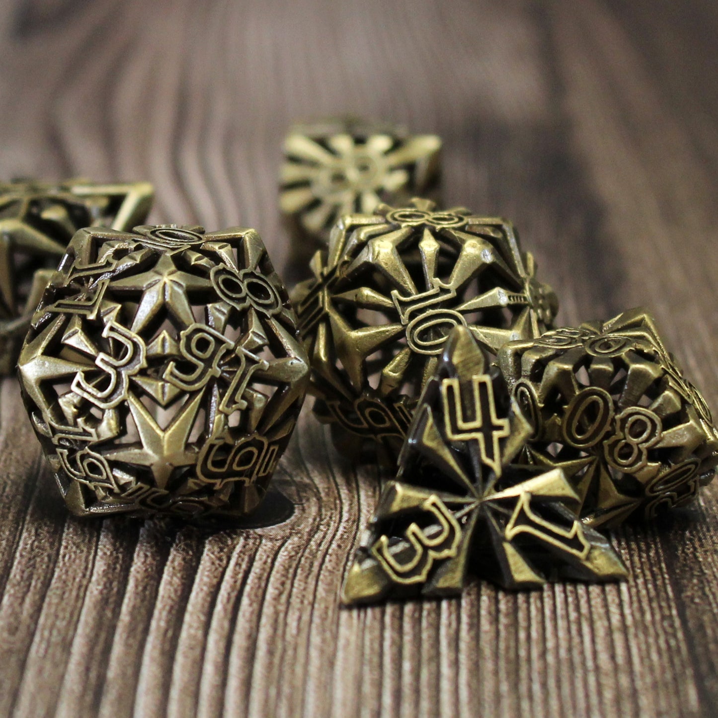 set of seven bronze cleric-inspired hollow metal dice with uninked numbers and a mace in place of the high number on each die on a wooden background