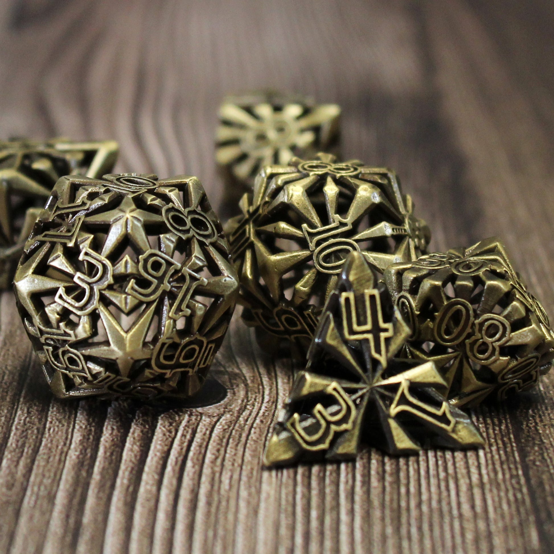set of seven bronze cleric-inspired hollow metal dice with uninked numbers and a mace in place of the high number on each die on a wooden background