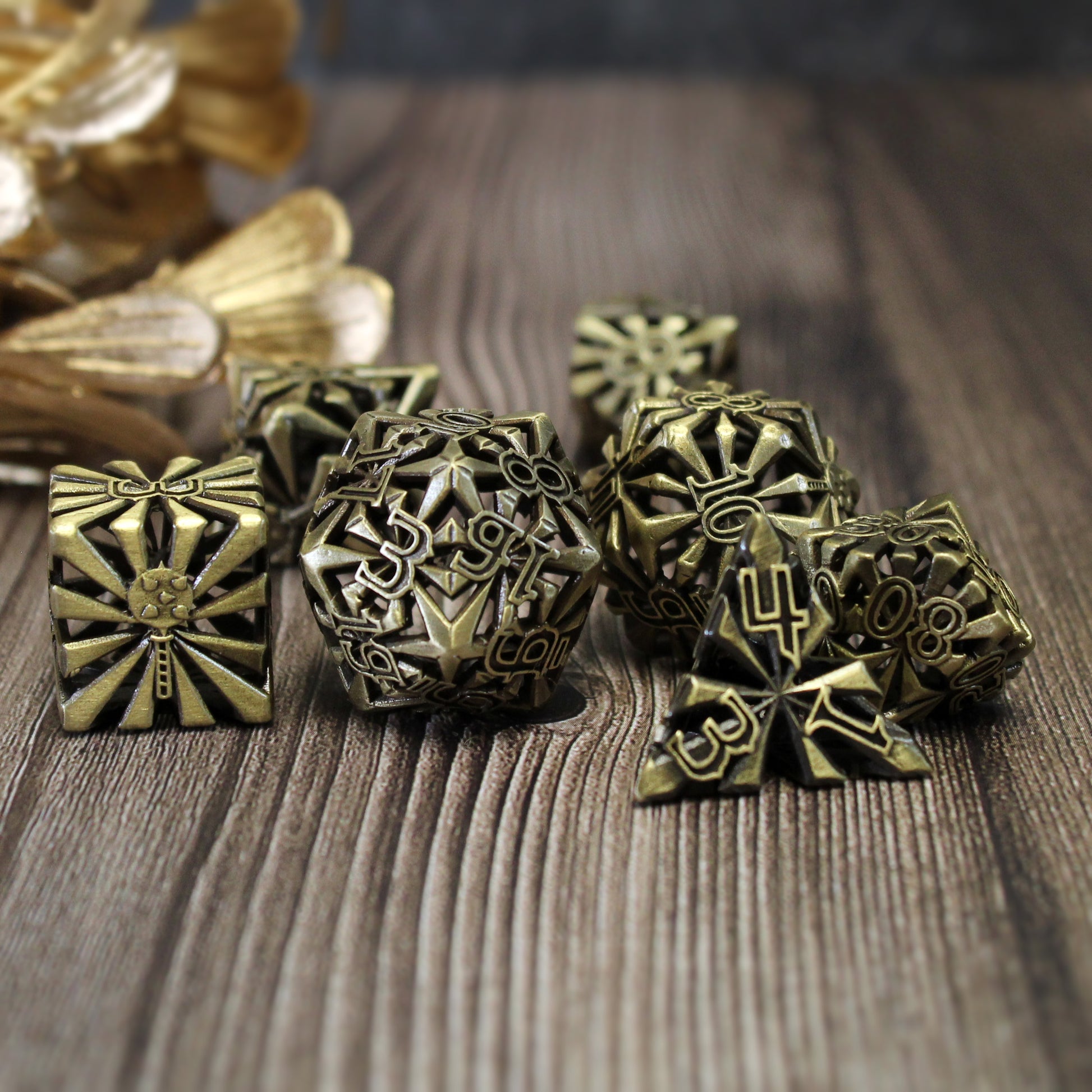 set of seven bronze cleric-inspired hollow metal dice with uninked numbers and a mace in place of the high number on each die on a wooden background