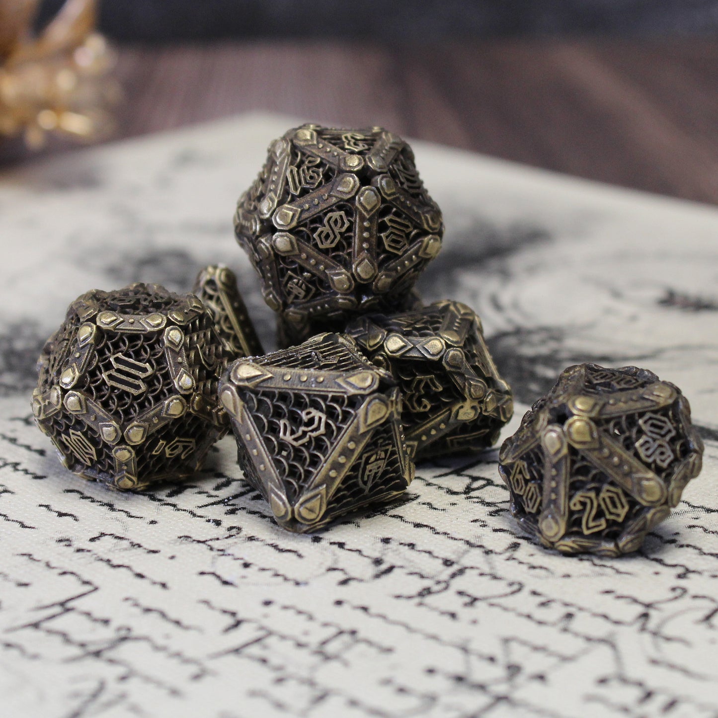 Set of bronze fighter-inspired hollow metal RPG dice with a chain mail background on each die face, uninked numbers, and a helmet, sword, and shield replacing the high number on each die on a handwritten page