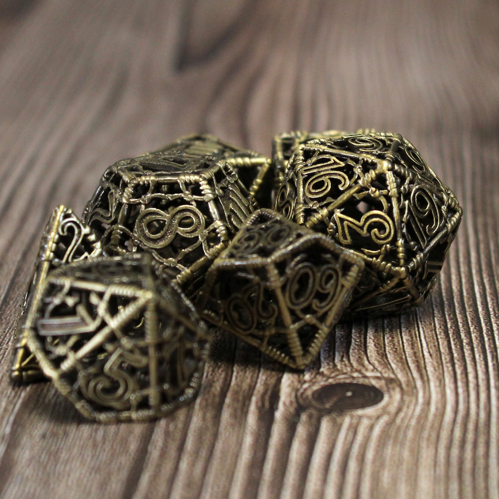 All 7 bronze dice clustered together on a wood paneled backrgound. Only the dice in the midground are in focus.