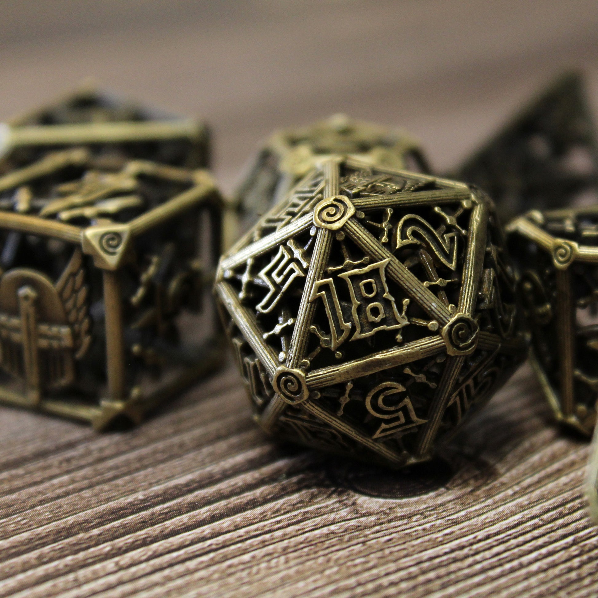 An up close image of a 20 sided die, with 5 other dice blurred in the background, all on a wood paneled surface.