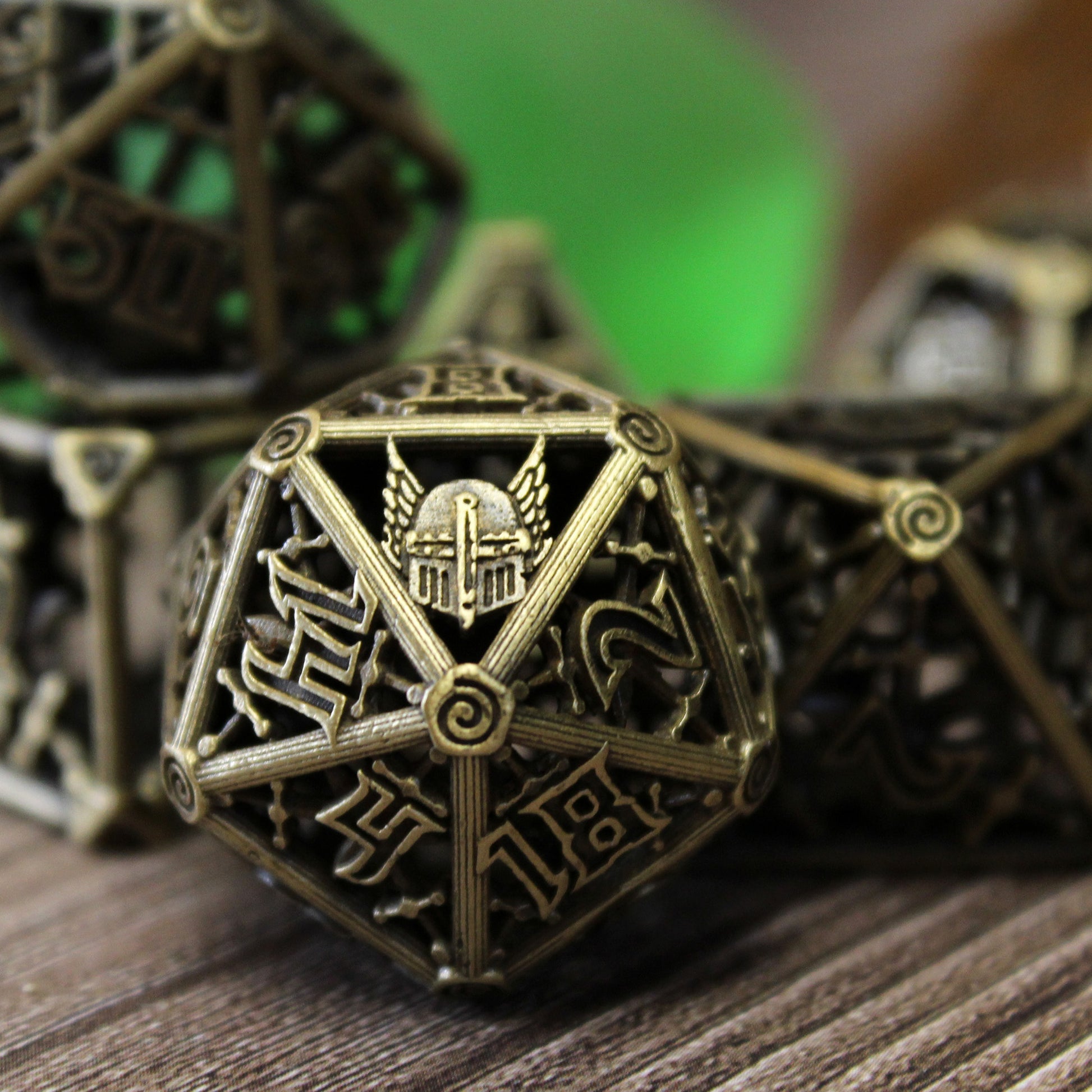 Up close image of 20 sided die, with 5 other dice blurred in background. On wooden paneled surface with a green and brown background.