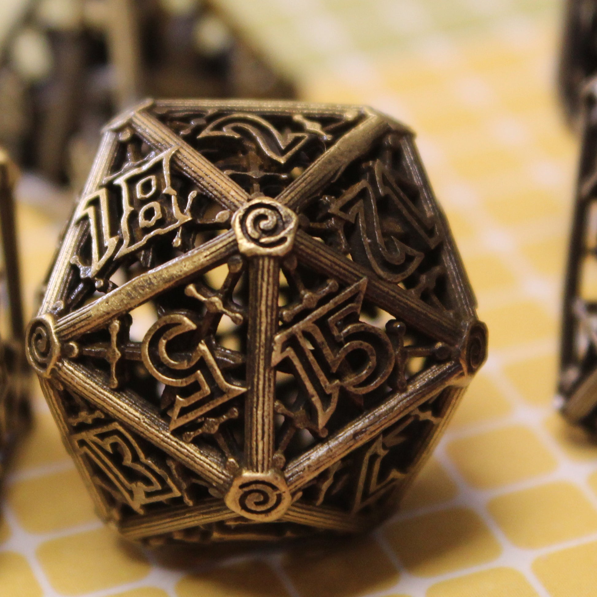 Up close image of bronze 20 sided die on a yellow tiled surface.