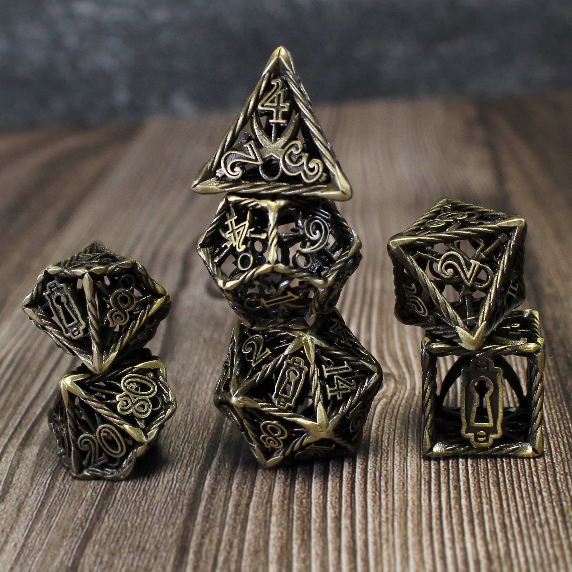 Bronze Rogue Cage dice set arranged in three columns on a wood surface.