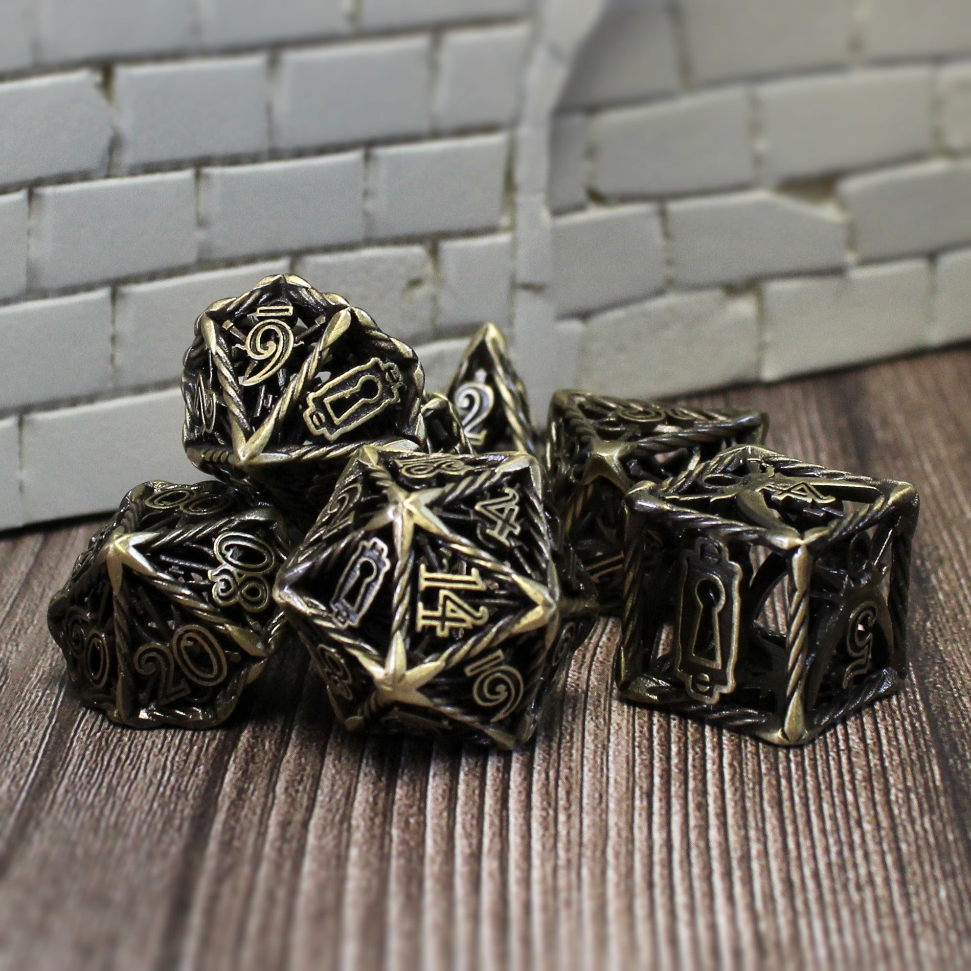 Bronze Rogue Cage dice set arranged in a pile on a wood surface with a white brick wall set pieces in the background.