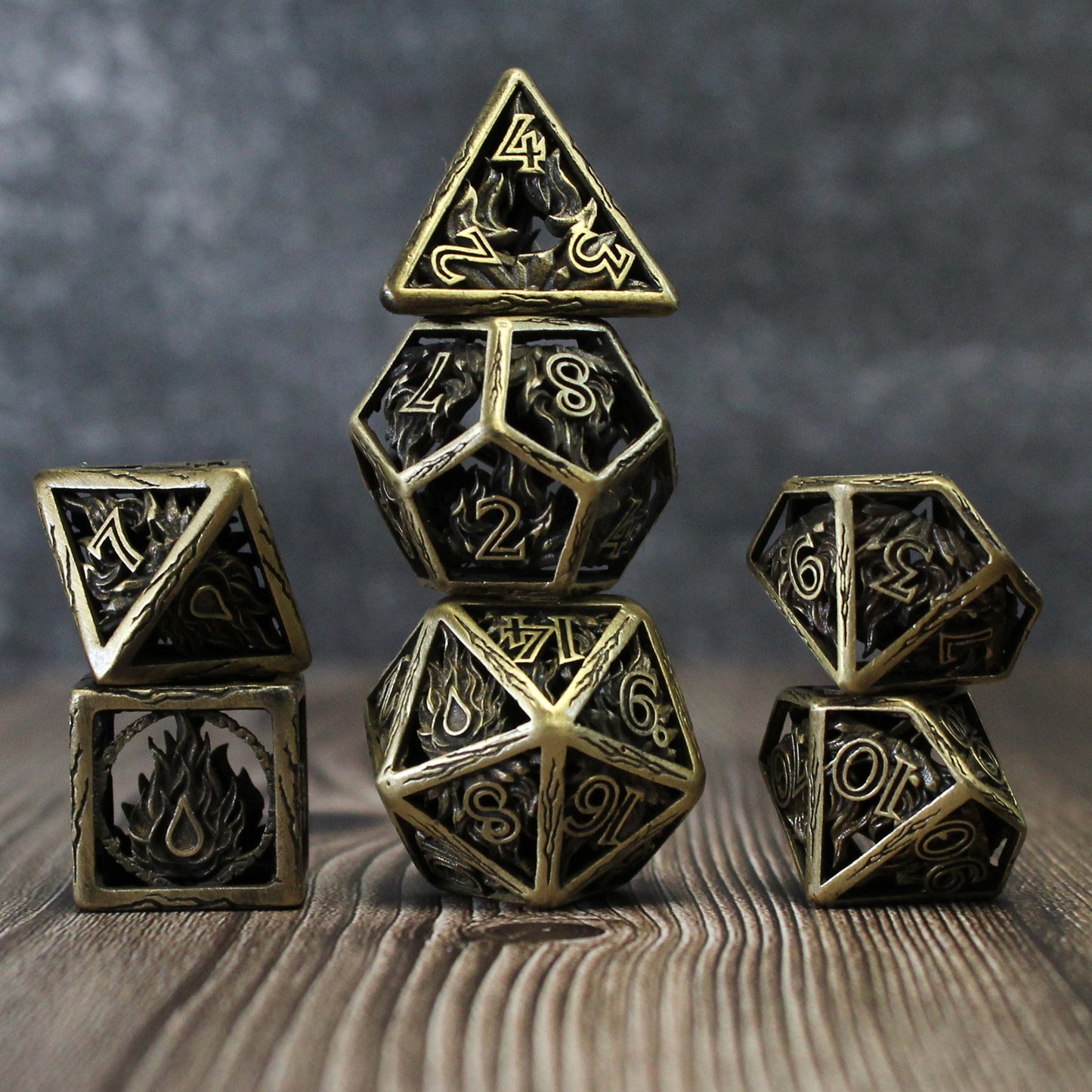 All 7 bronze dice piled up in 3 stacks. Two dice in first stack, three dice in second stack, two dice in third stack. All on wood paneled surface with a grey background.
