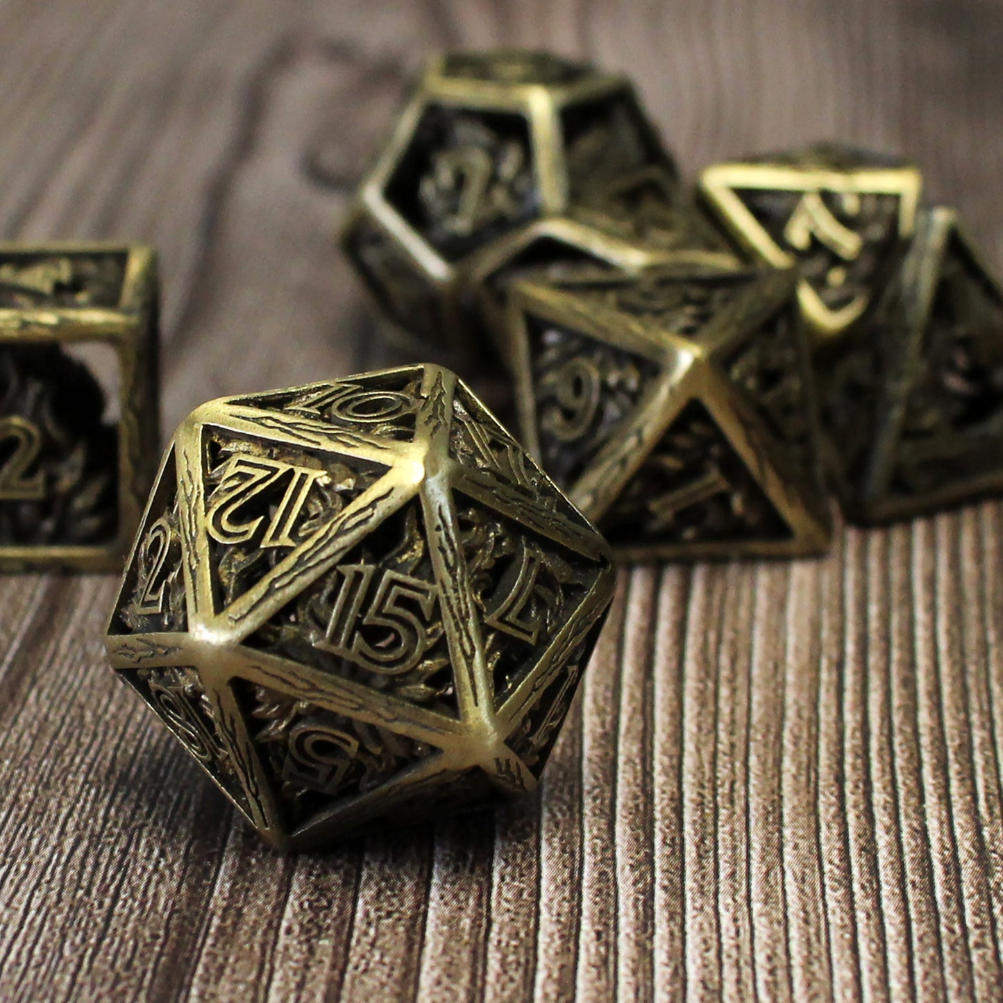 20 sided die in foreground, with 5 other dice blurred in background. All on a wood paneled surface.