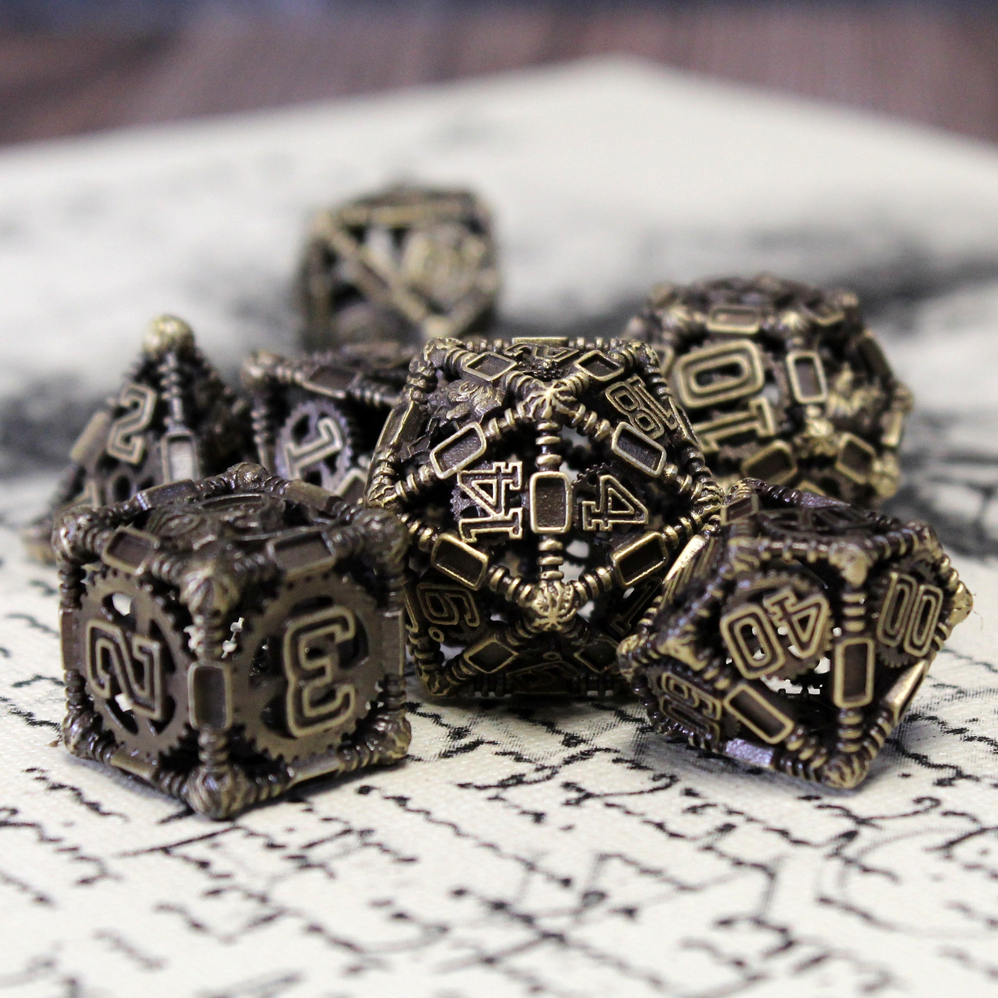 20 sided die in focus with other dice in set blurred around it. Displayed on top of a piece of cloth with cursive on it.