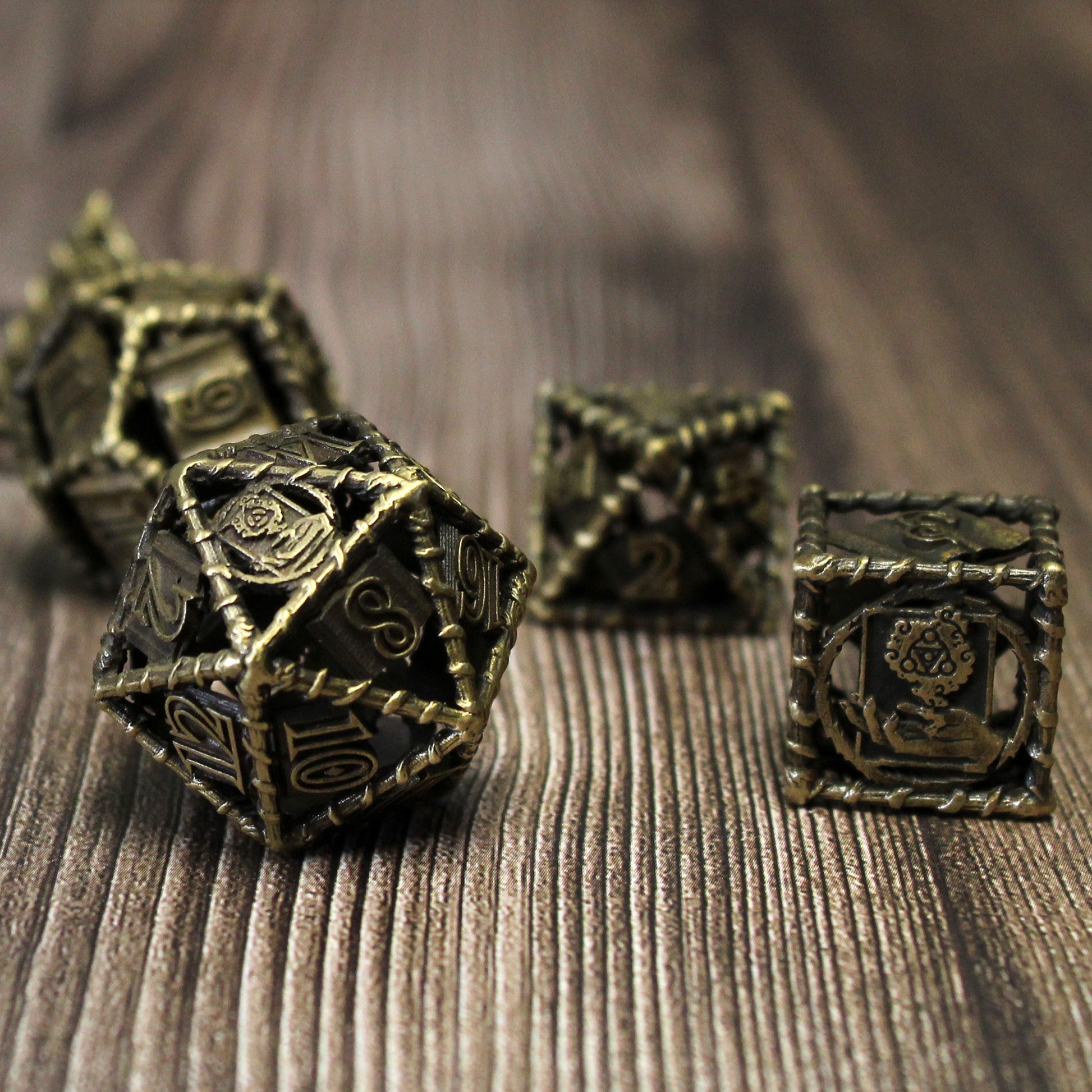 bronze 20 sided die and 6 sided die in foreground, with three other dice scattered in background. On a wood paneled surface.