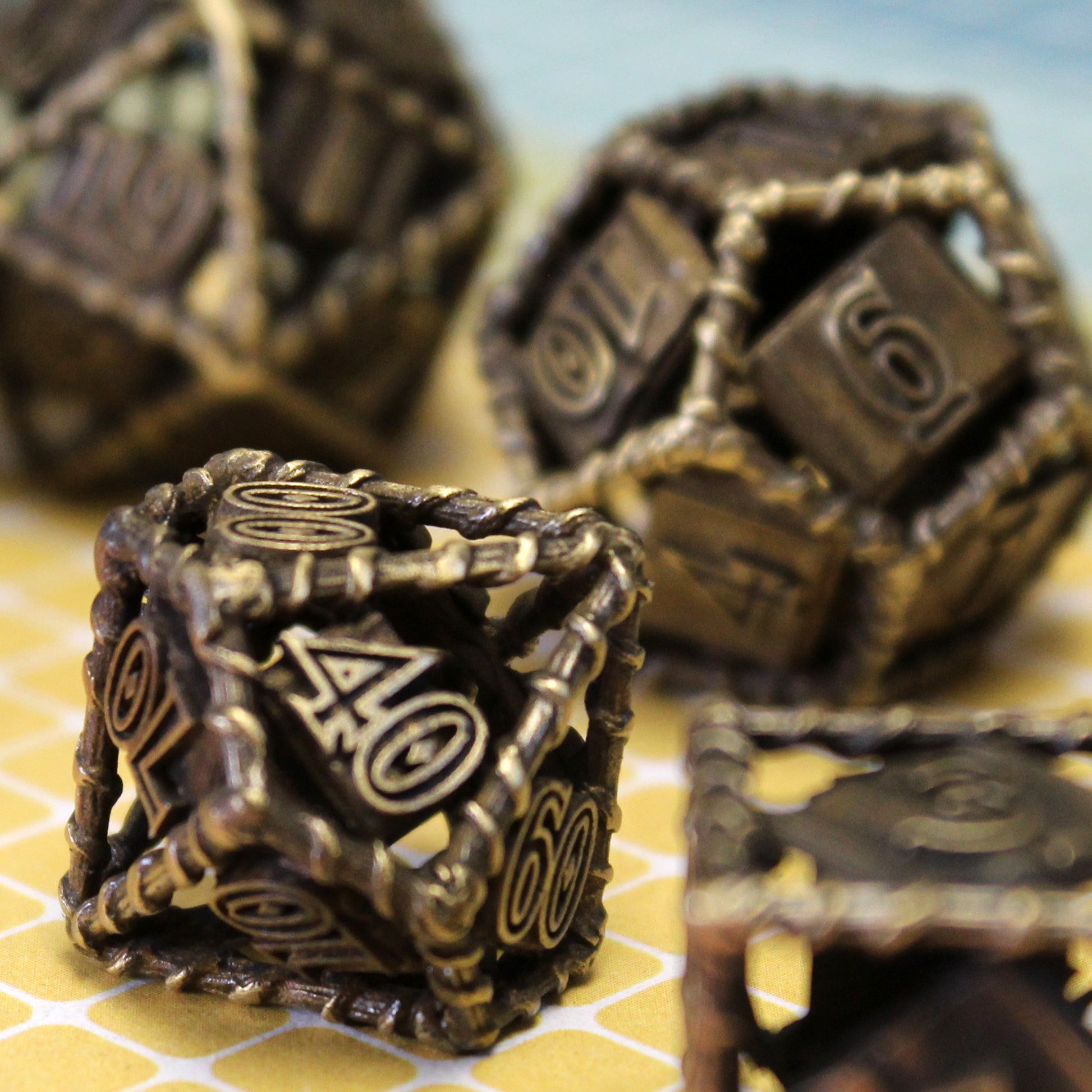 10 sided die in focus with three other dice  scattered and out of focus, all on yellow tiled surface with light blue background.