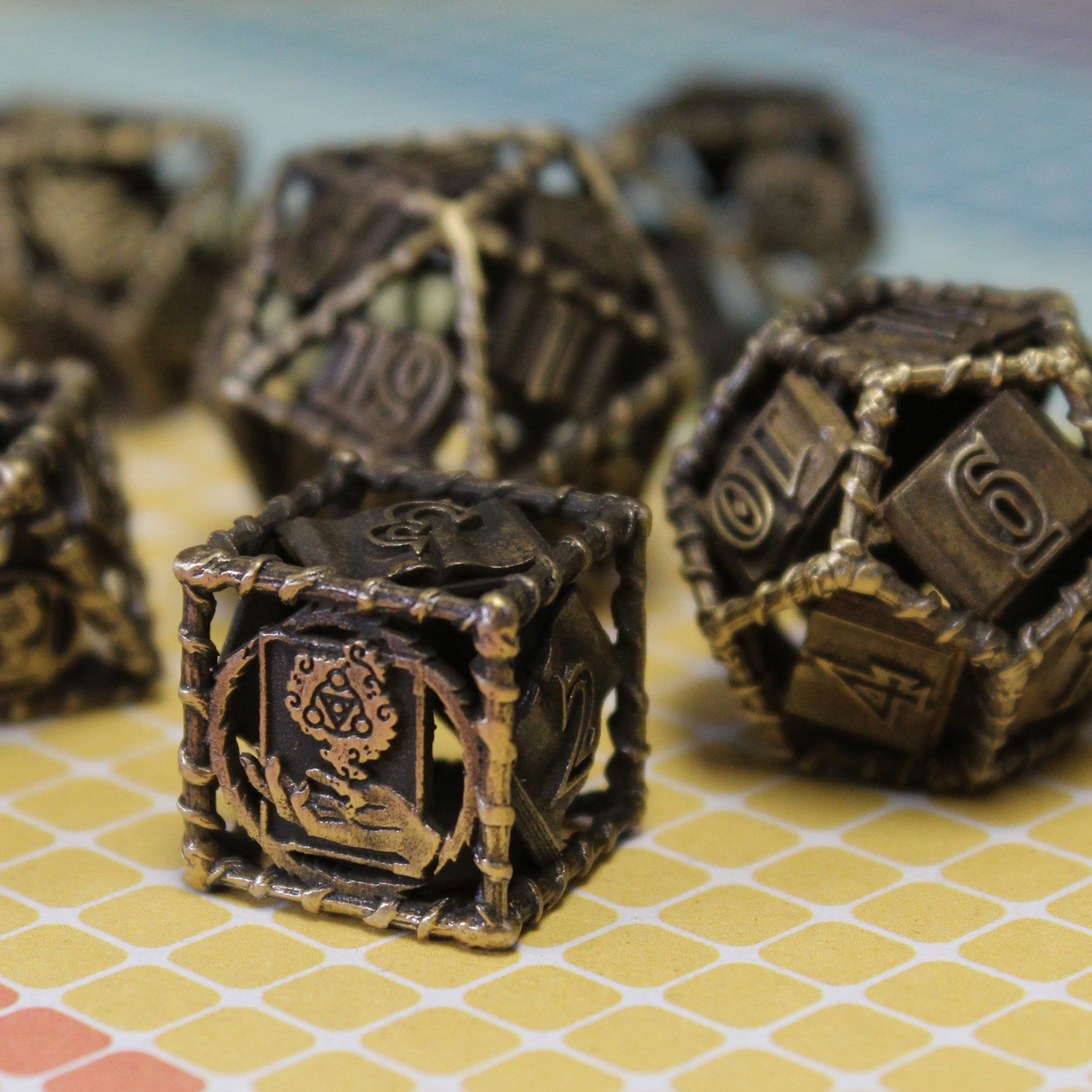 12 and 6 sided dice in focus with other dice in set blurred in background. On a yellow tiled surface with a light blue background.