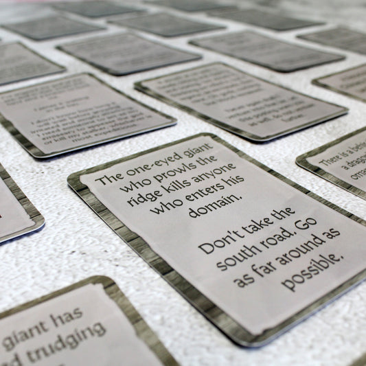 Array of Colossal Terrors quest cards displayed on a table, each card featuring prompts for tracking and battling colossal monsters in RPG campaigns.