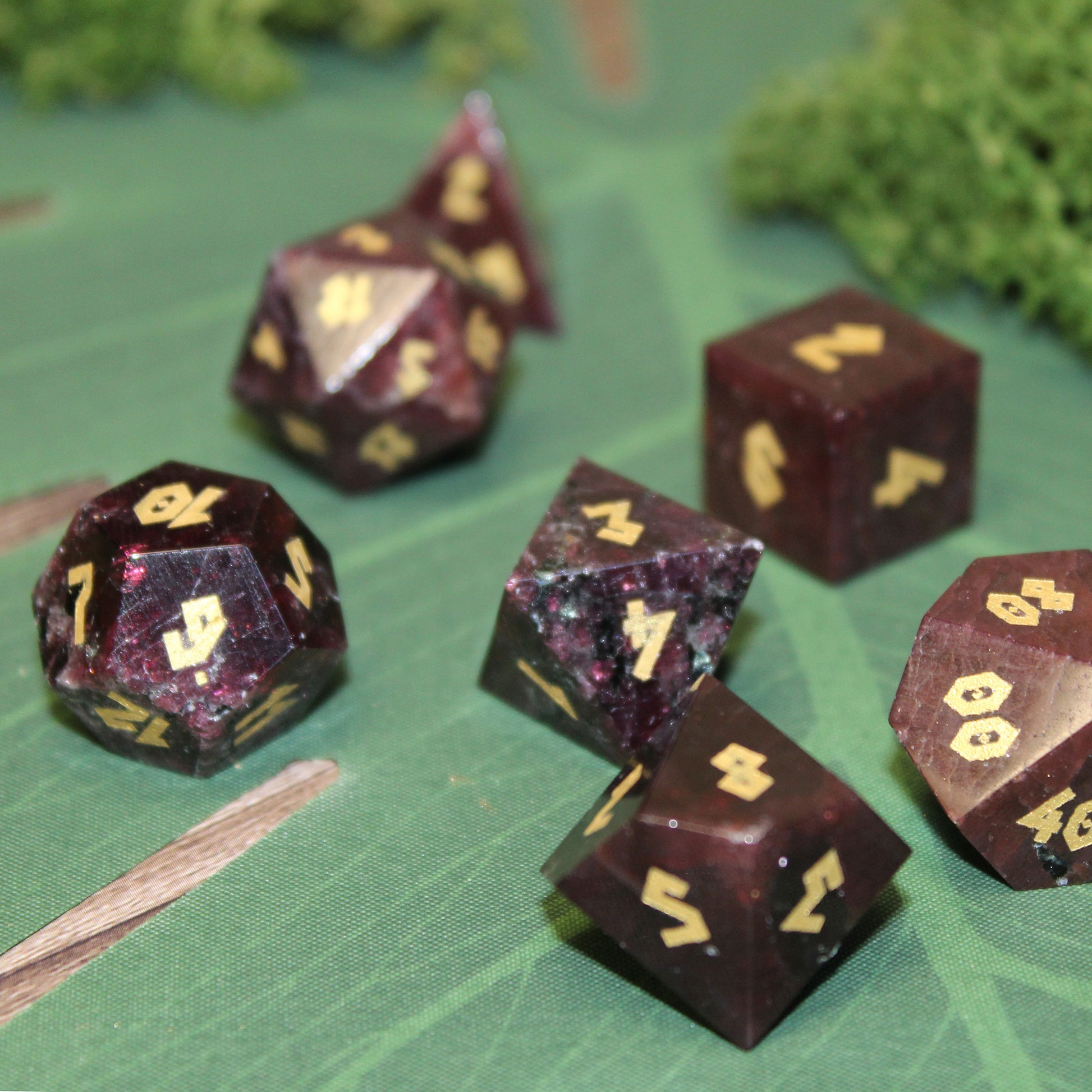 Raw Garnet gemstone dice set on a table, showcasing the rich red color and gold numbering for RPG adventures.