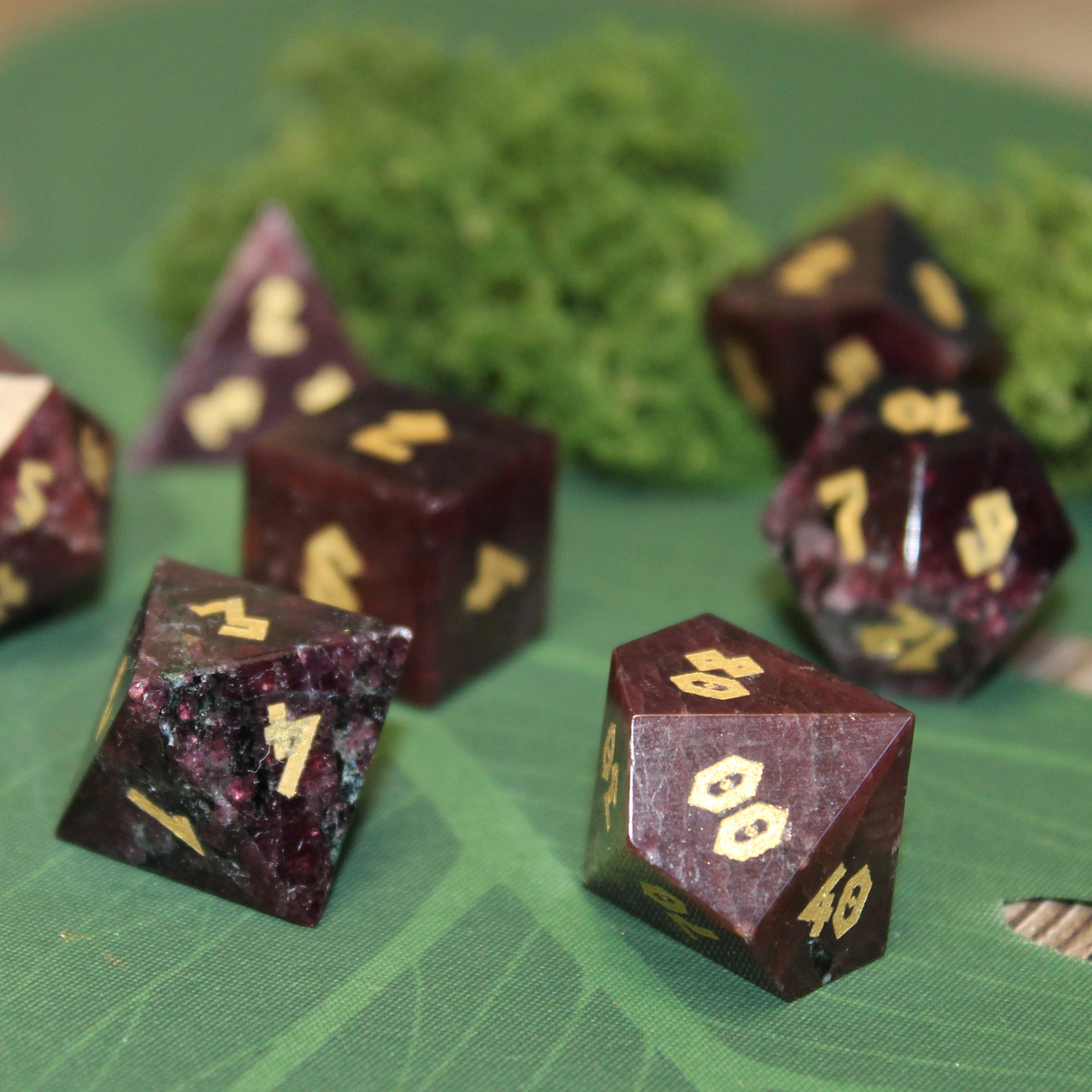 Scattered Garnet gemstone dice set, displaying the natural deep red hues and elegant gold numbering.
