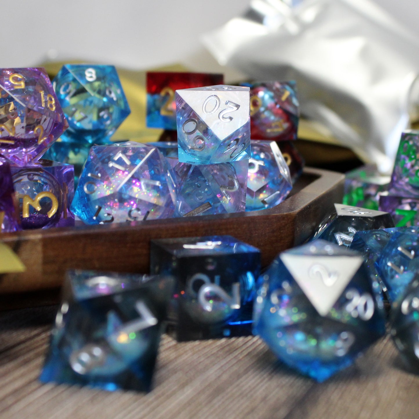 A zoomed in image of liquid core resin dice available in the mystery liquid core set in a wooden tray with mylar bags in the background.