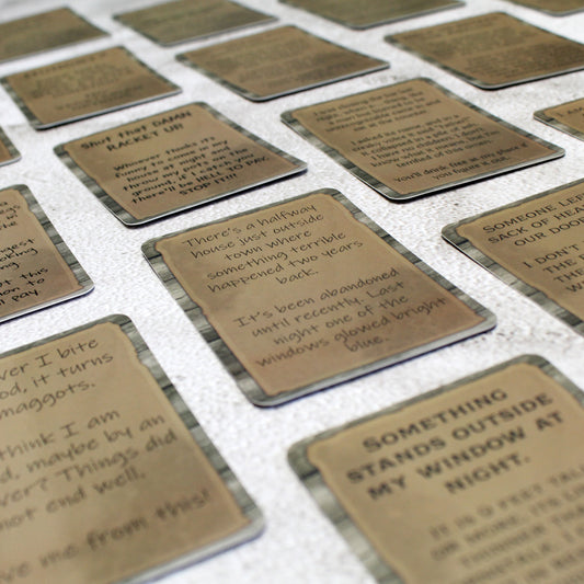 A spread of cards from the Horror & Mystery Quest Deck with postings presented as aged paper on a wooden board background in various fonts.  
The central card reads, "There's a halfway house just outside of town where something terrible happened two years back.
It's been abandoned util recently.  Last night one of the windows glowed bright blue."