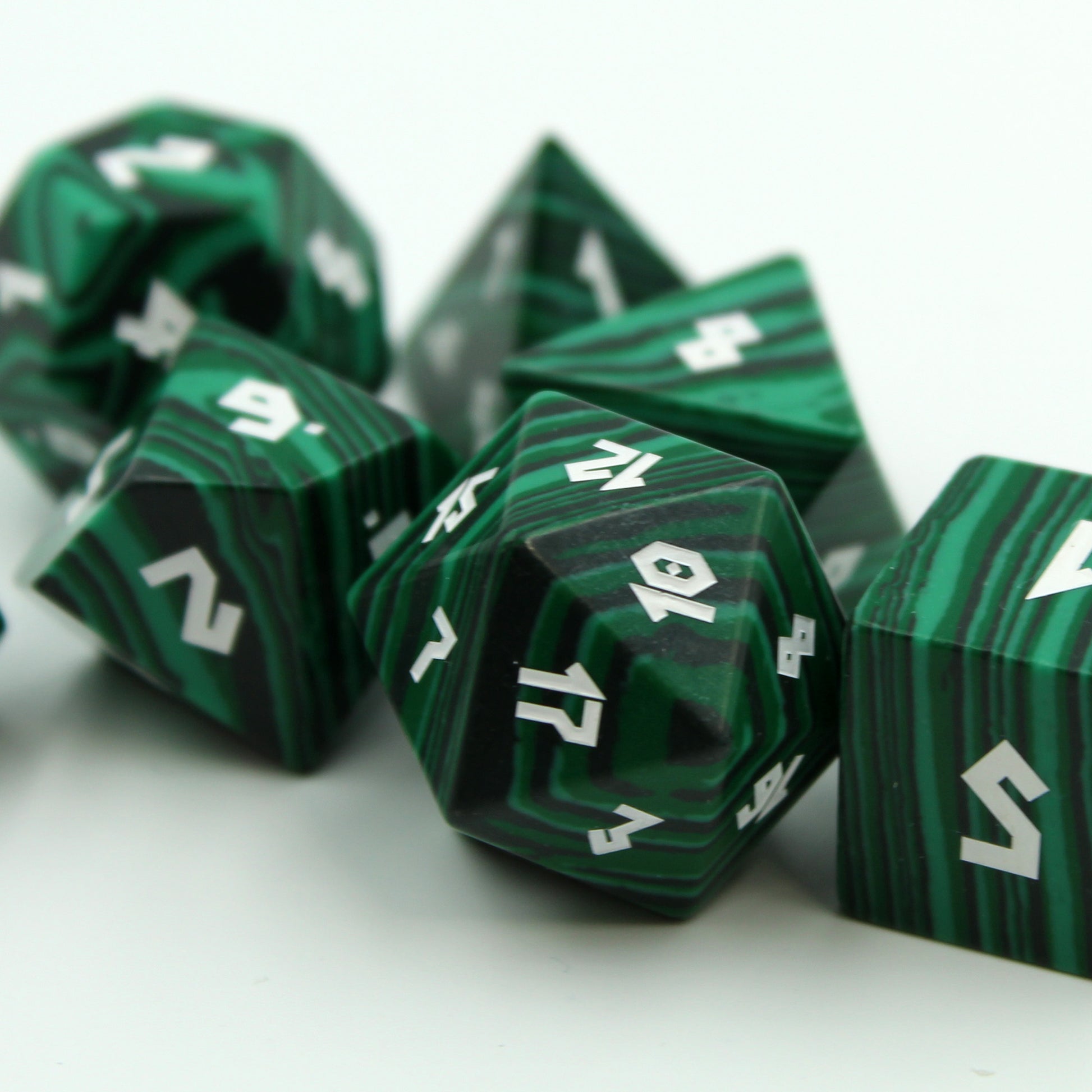 Zoomed-in image of the dice set on white, emphasizing green to black coloration and intricate golden numbers for Dungeons and Dragons.