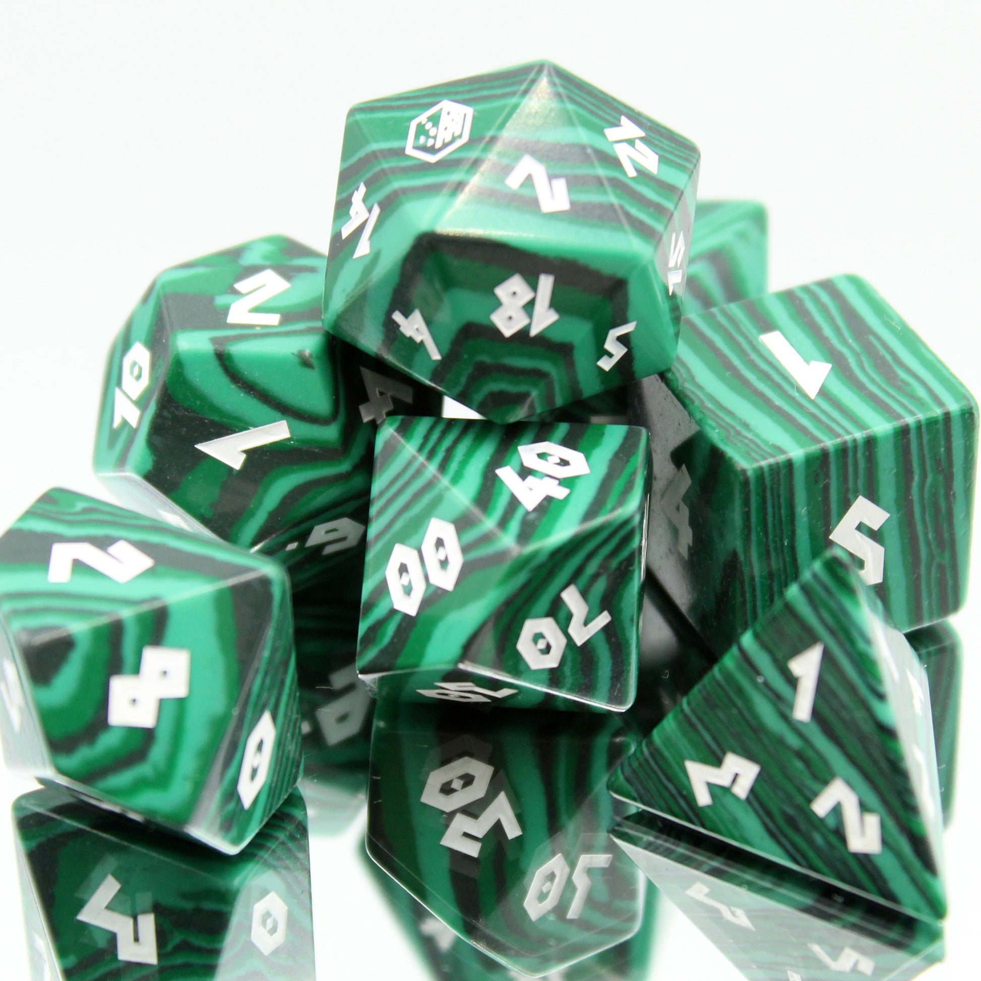 Faux Malachite dice set tightly grouped on a mirror, showcasing medium green to black patterns with golden numbering for DnD.