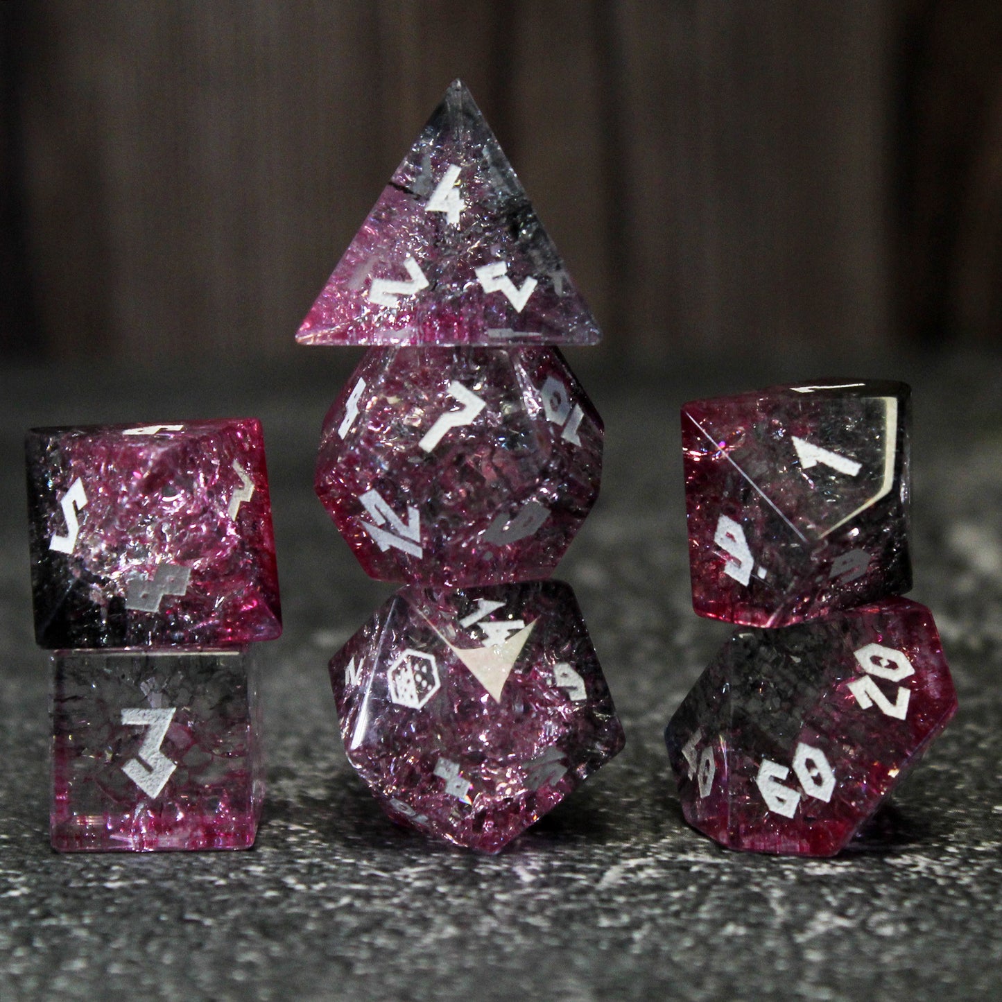 Three stacks of glass dice on a grey background, highlighting the pink and black color throughout.