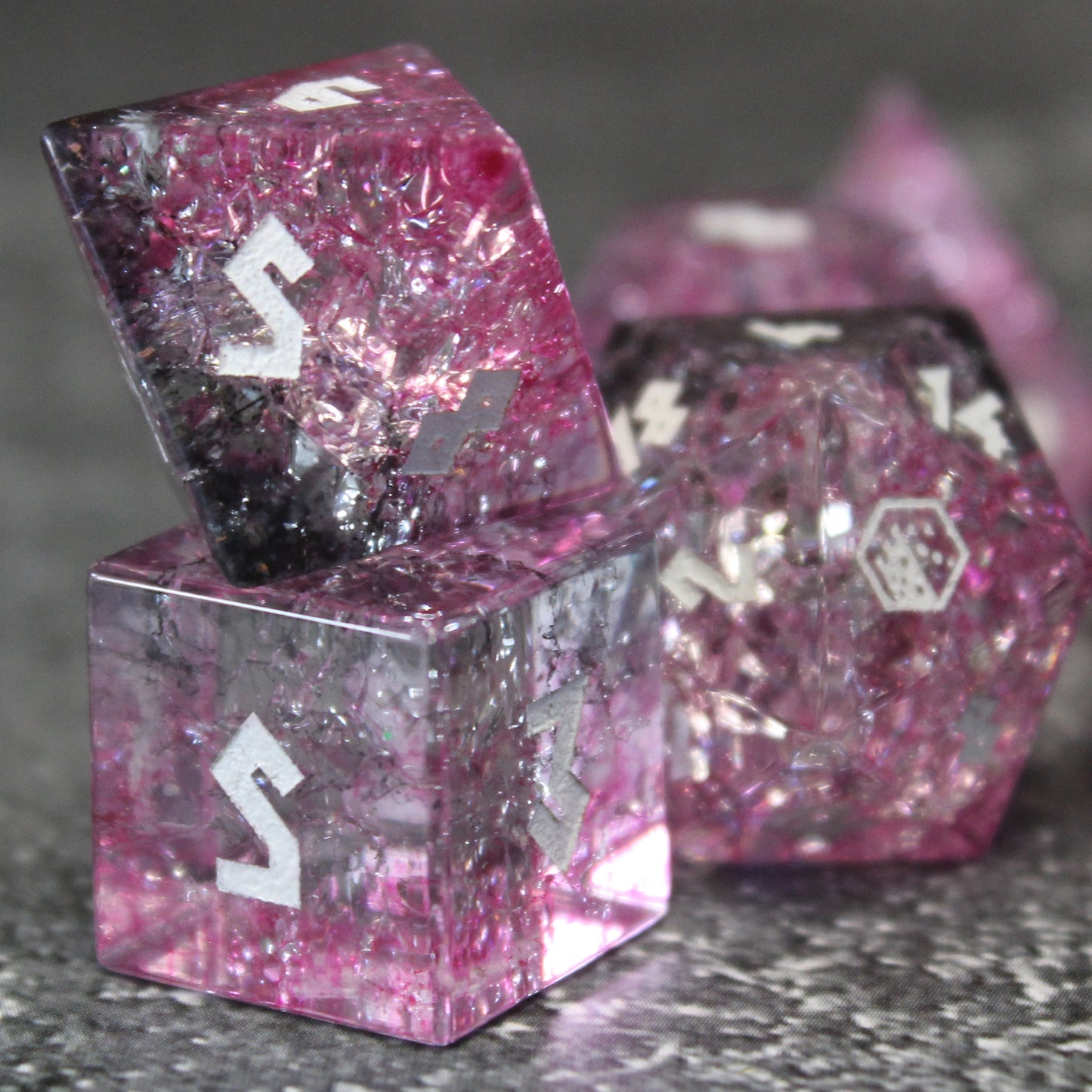 Closeup of Glass dice set highlighting the light refracting through pinks and black.