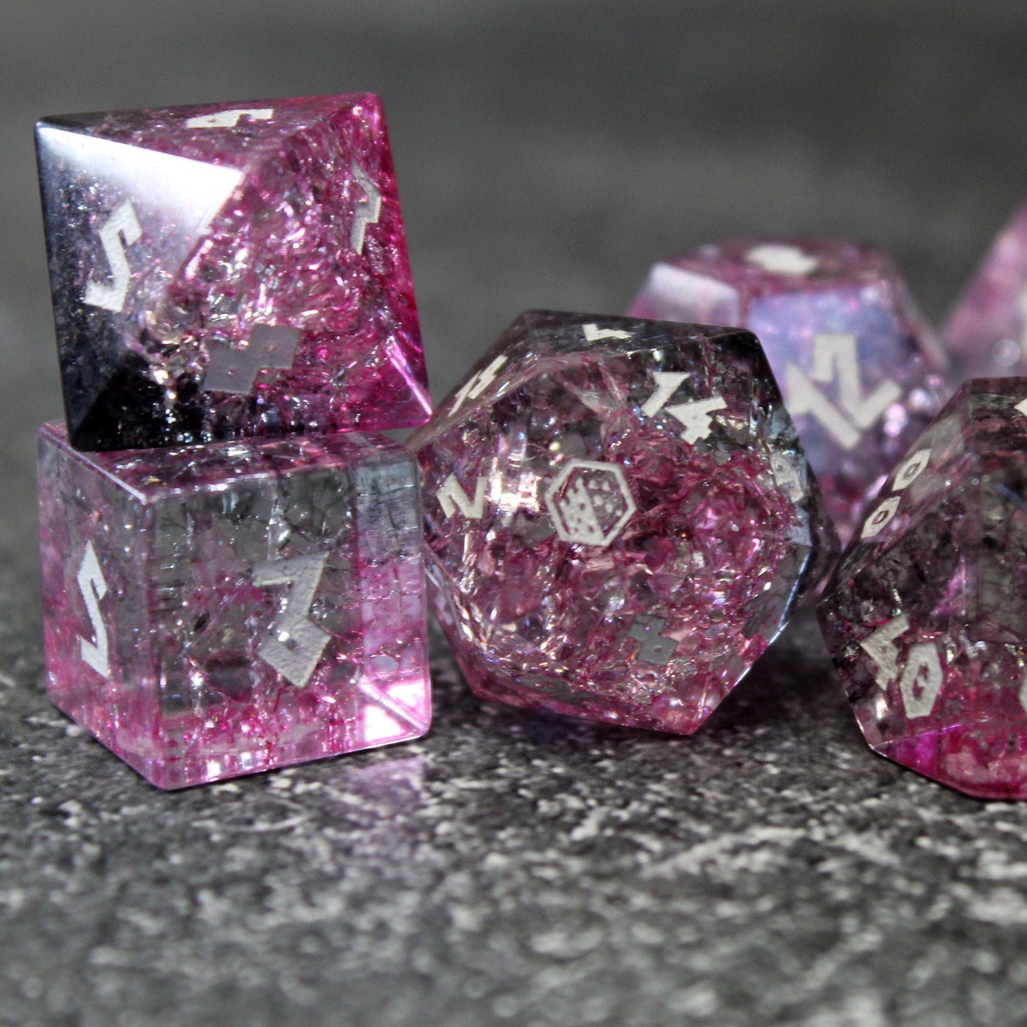 Closeup of Glass dice set highlighting the light refracting through pinks and black.