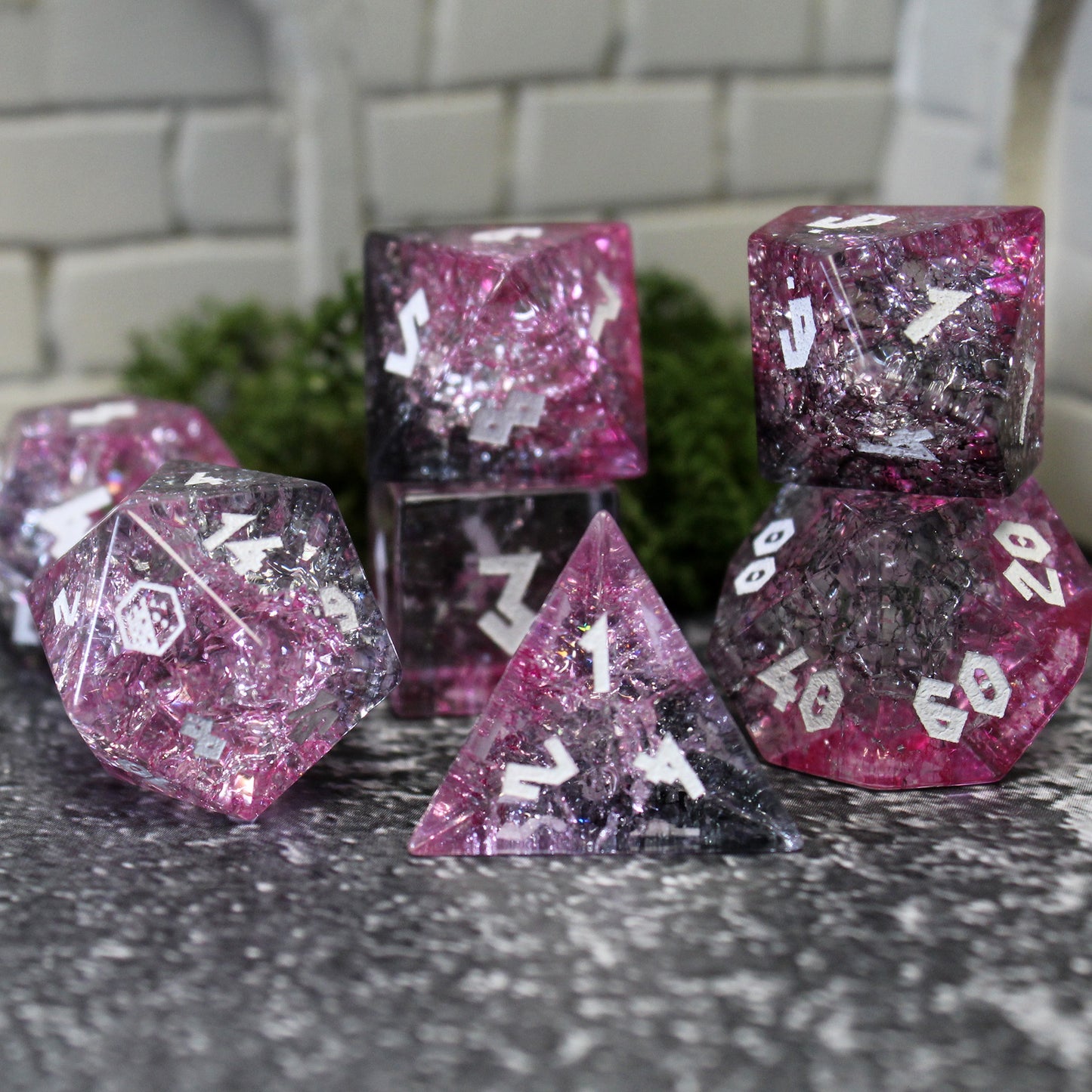 Set of Glass dice on counter top, highlighting pink and black insides as well as white numbers.