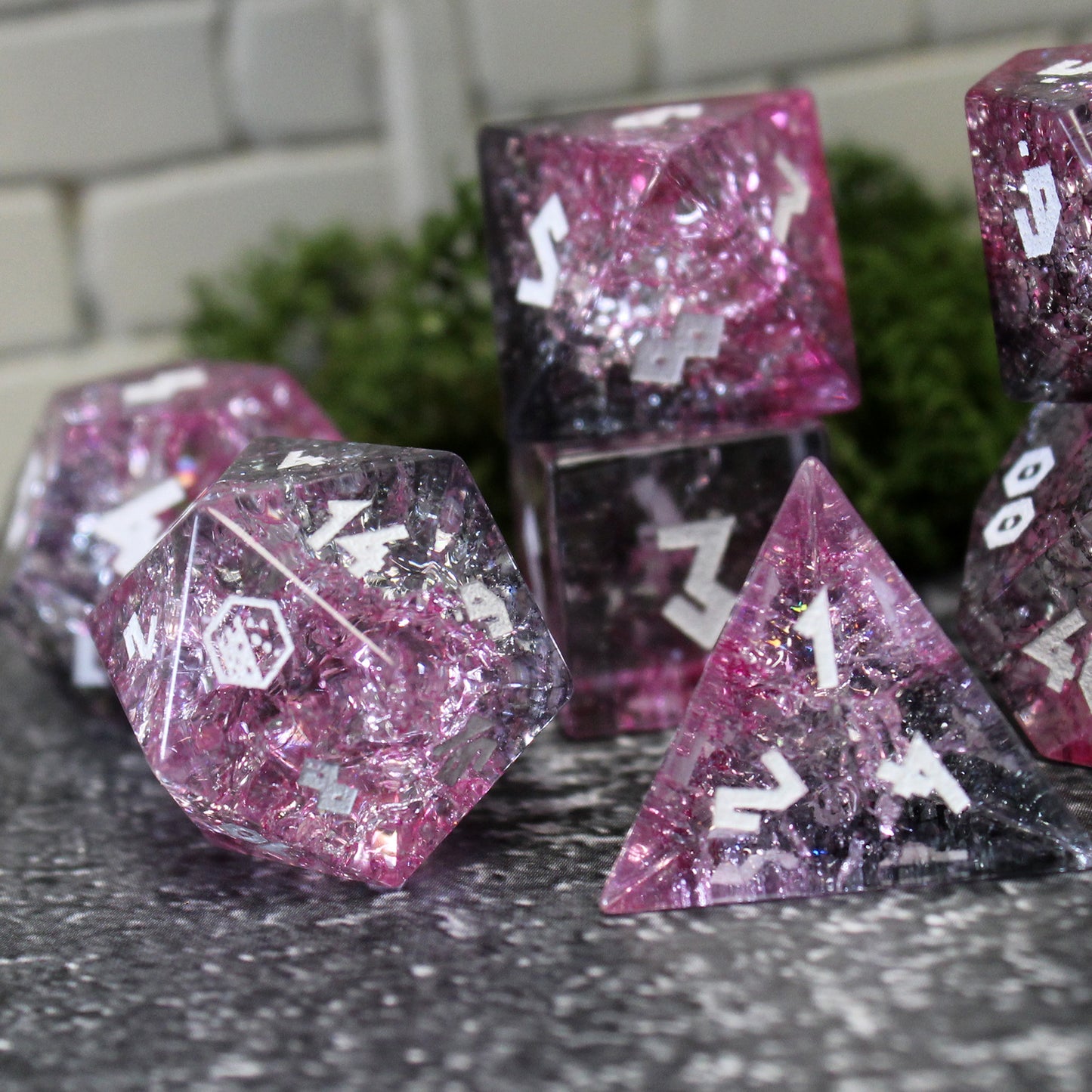 Closeup of Glass dice set highlighting the light refracting through pinks and black.
