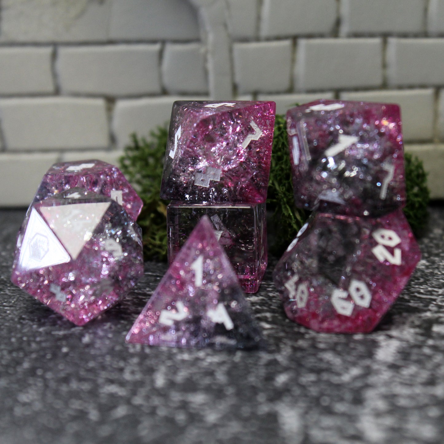 Closeup of Glass dice set highlighting the light refracting through pinks and black.