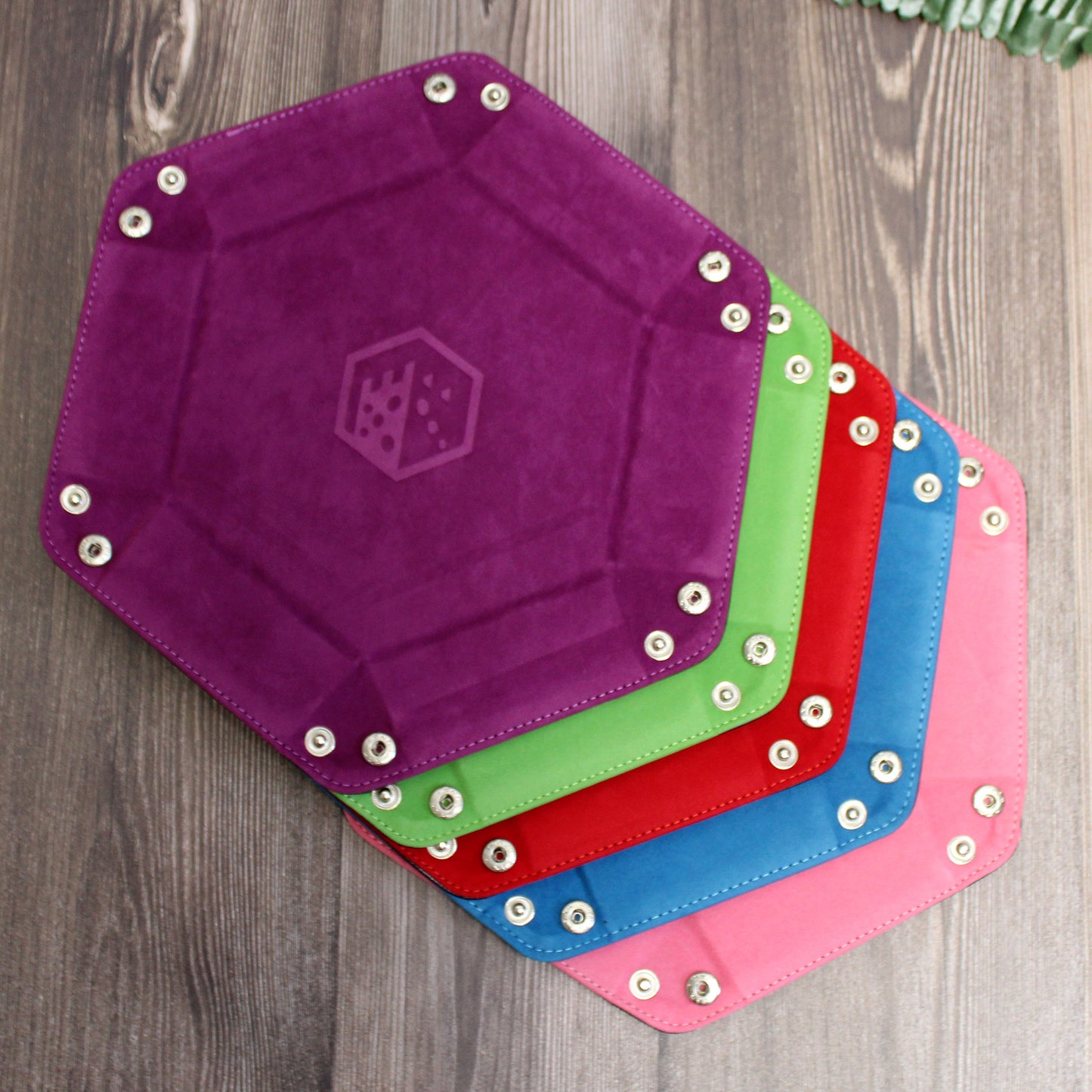 All color options of the Folding Hexagonal Dice Trays arranged flat in a rainbow pattern on a wooden background, displaying the variety of vibrant colors.