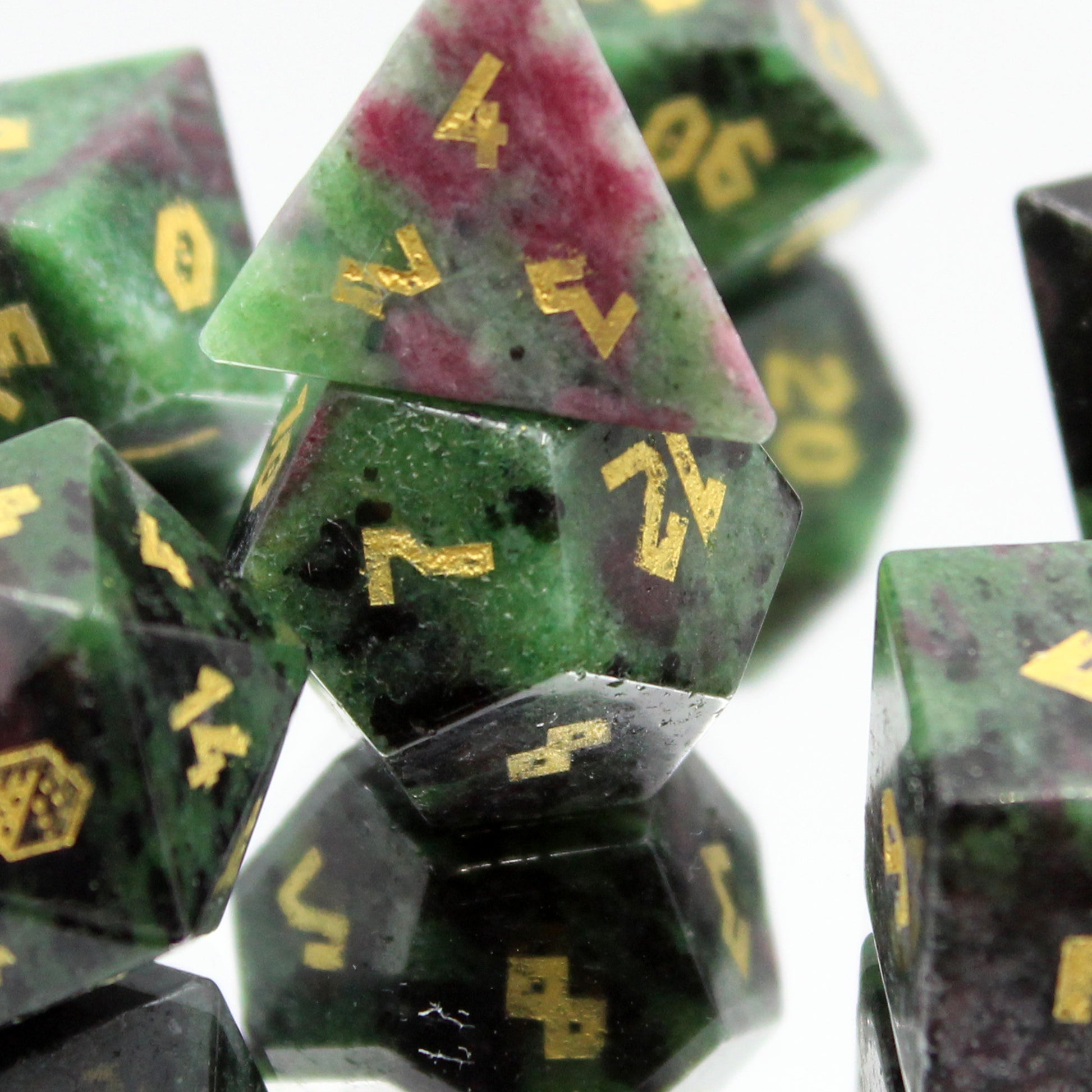 Close-up of Ruby Zoisite D12 and D4 dice on a mirror, showcasing natural stone patterns and vibrant colors for DnD.