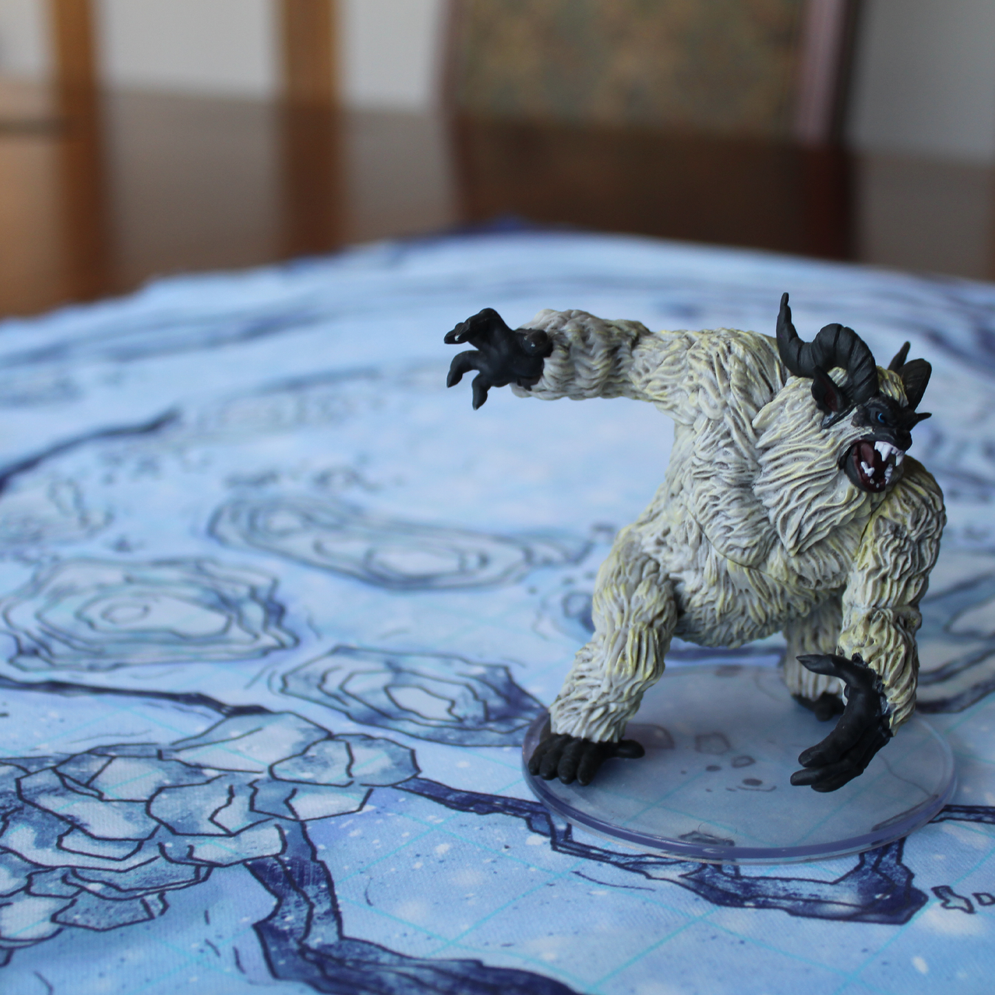 Closeup photo of a snowy battle map with a miniature yeti figure on it