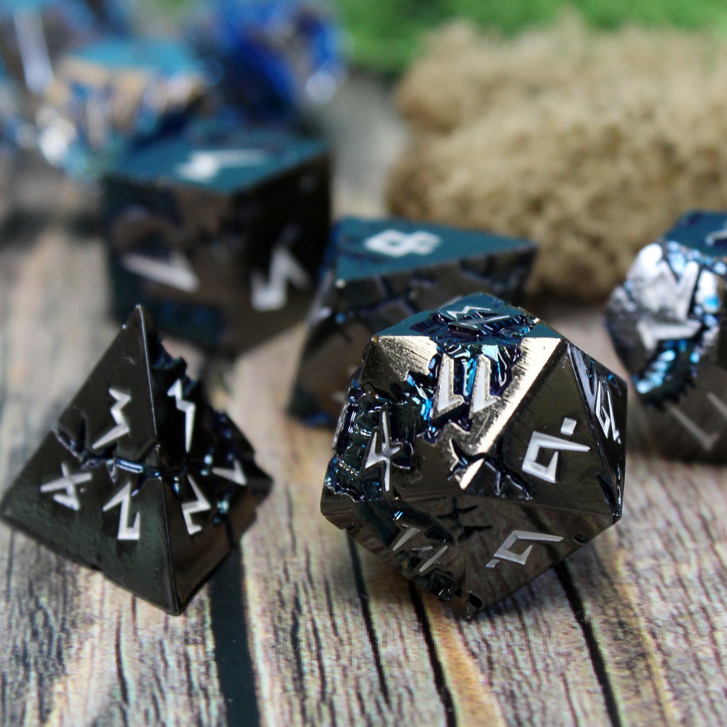 Close-up of Stormrift black nickel D20 and D4 on wood, highlighting deep blue scars and white jagged numbers, perfect for RPG enthusiasts.