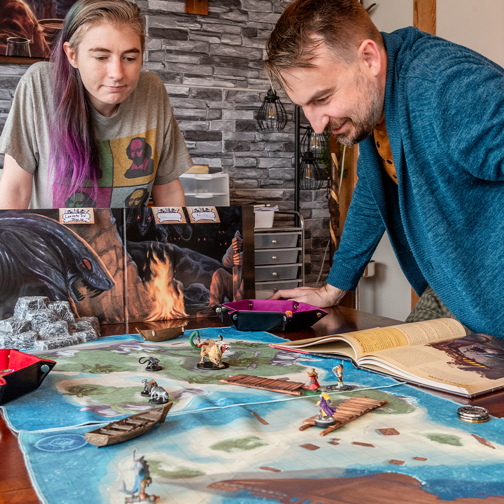 Photo of two people playing a tabletop RPG using a battle map depicting a sunken ship