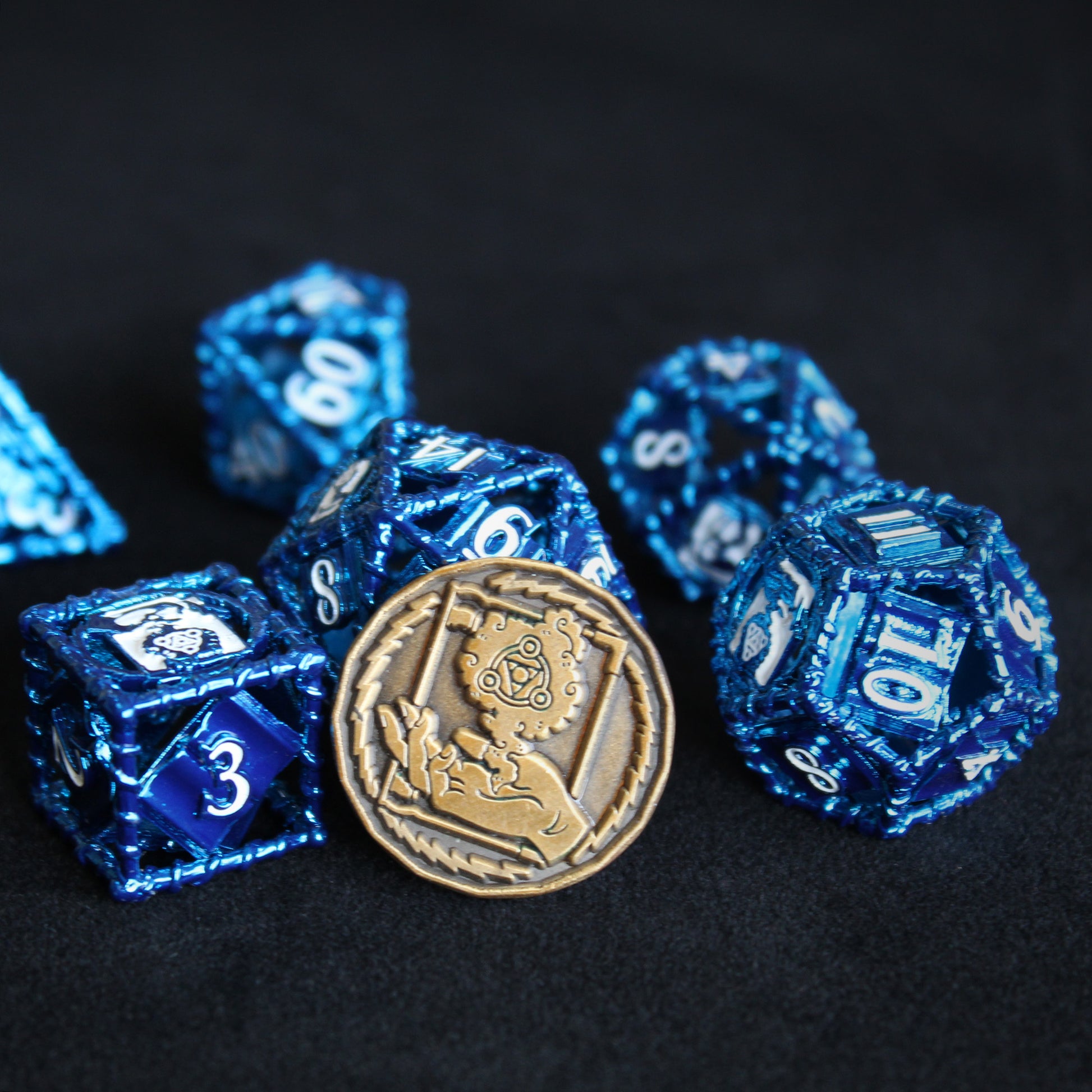 a gold wizard character coin propped up on blue 20 sided die, with other 6 die in set scattered around, all on black background.