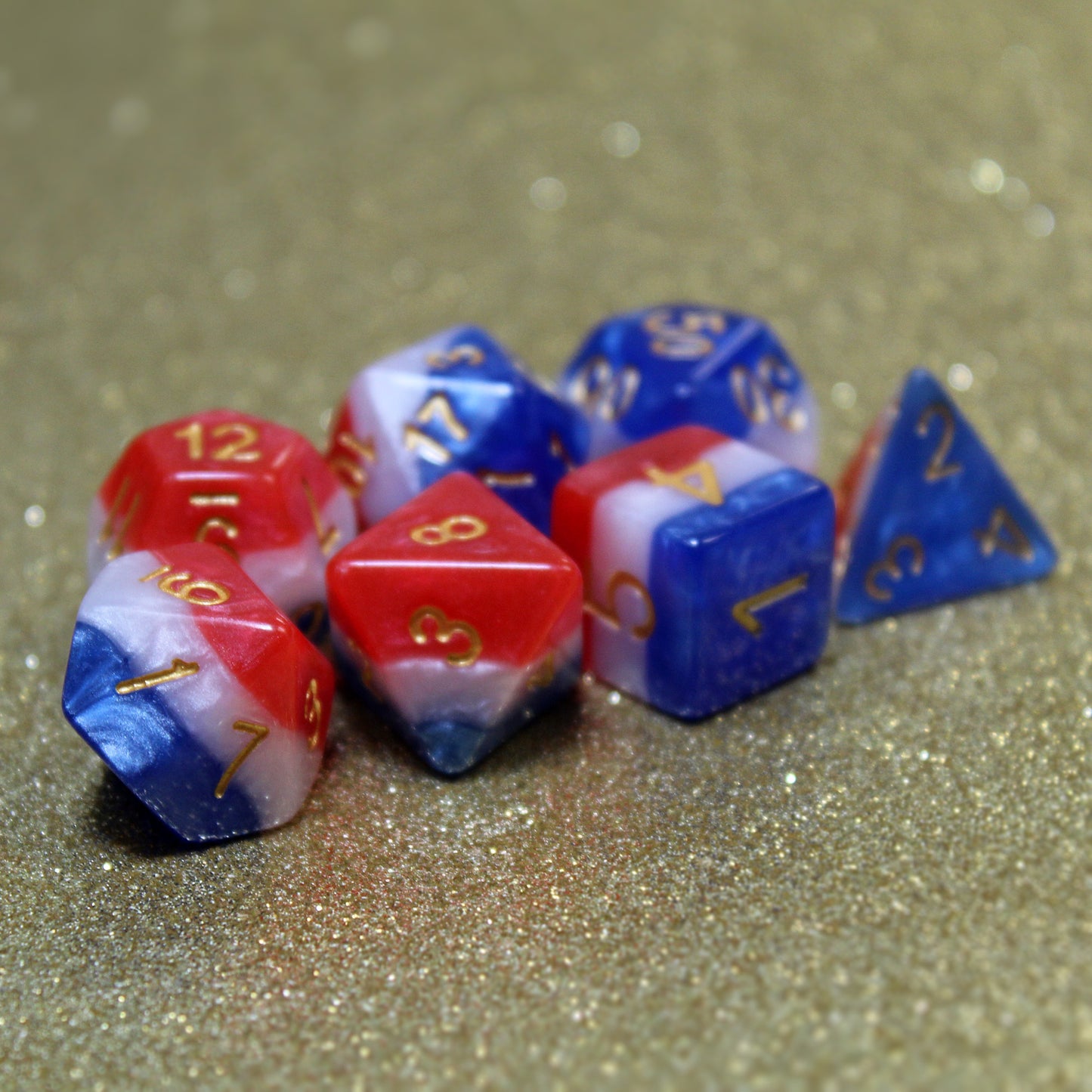 The red, white, and blue layered dice set resting on a gold background, showcasing the dice's colors and the easy-to-read gold numbers.