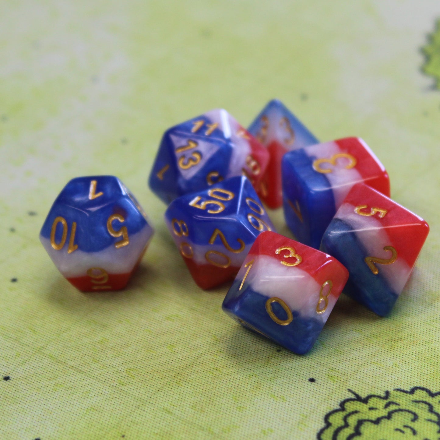 Layered red, white, and blue dice set scattered across a forest battle-map, showing the mix of colors and the clear gold numbers.