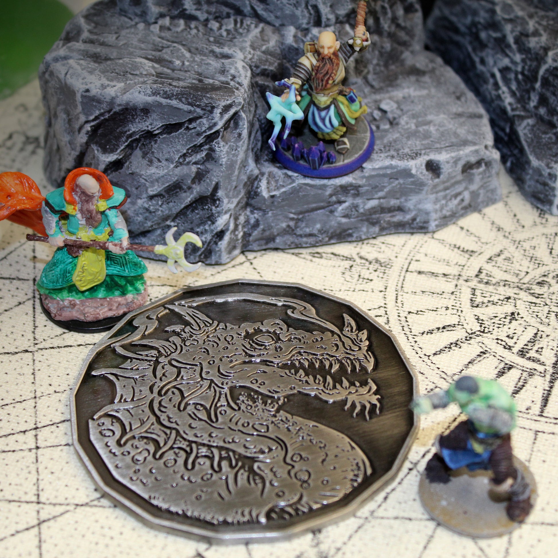 Adult Smoke Dragon monster token on a D&D table with scattered miniatures, showing the antique silver finish.