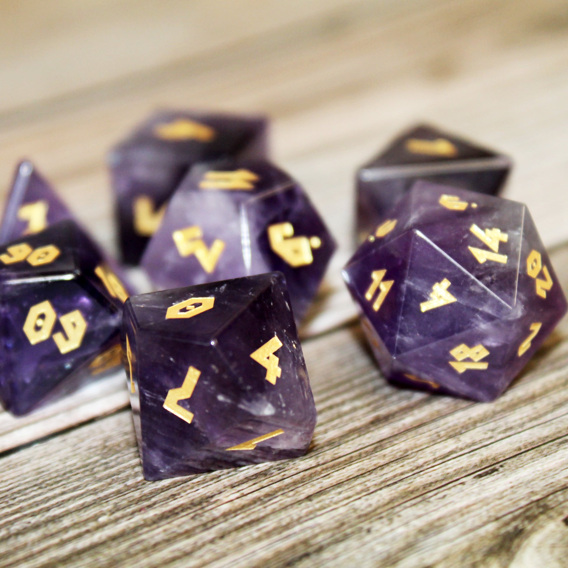 Amethyst dice set displayed on a wooden surface, showing natural variations of the stone.