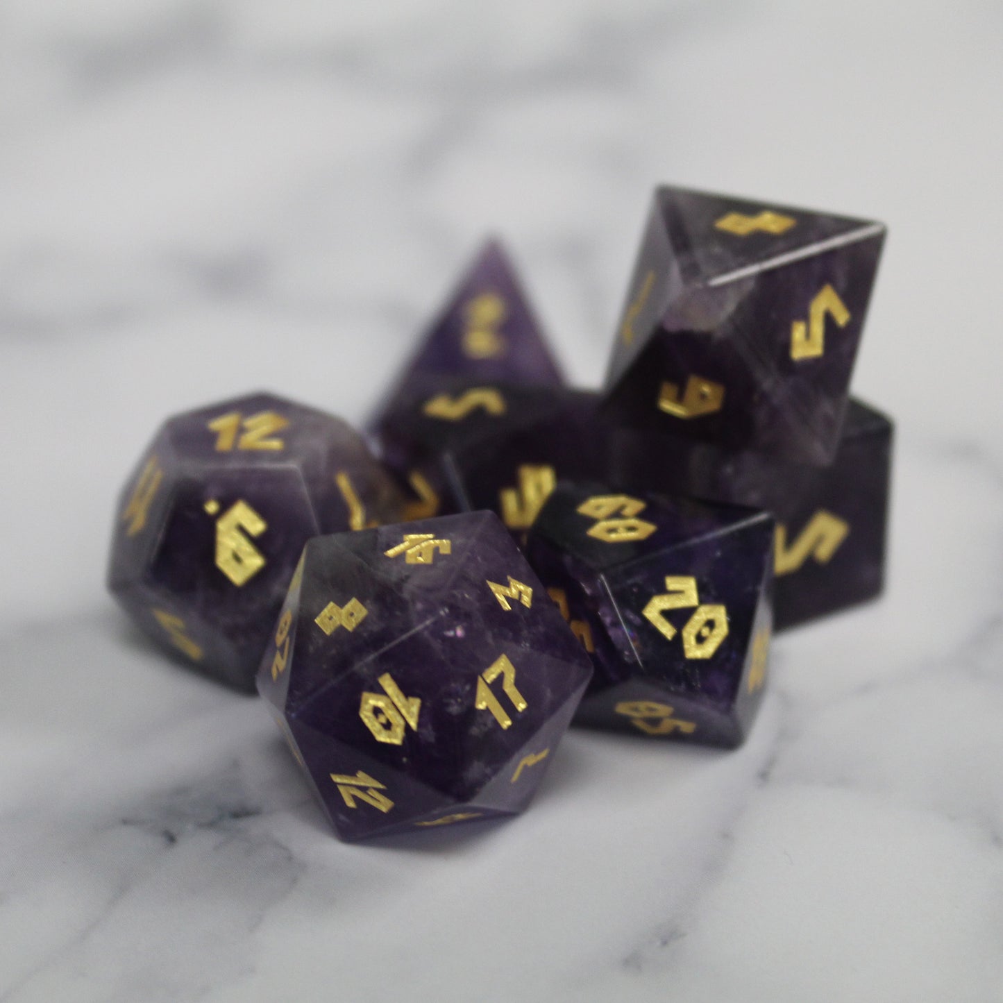 Amethyst dice set displayed on a marble surface, showing the high-quality gemstone craftsmanship and vibrant indigo tones.