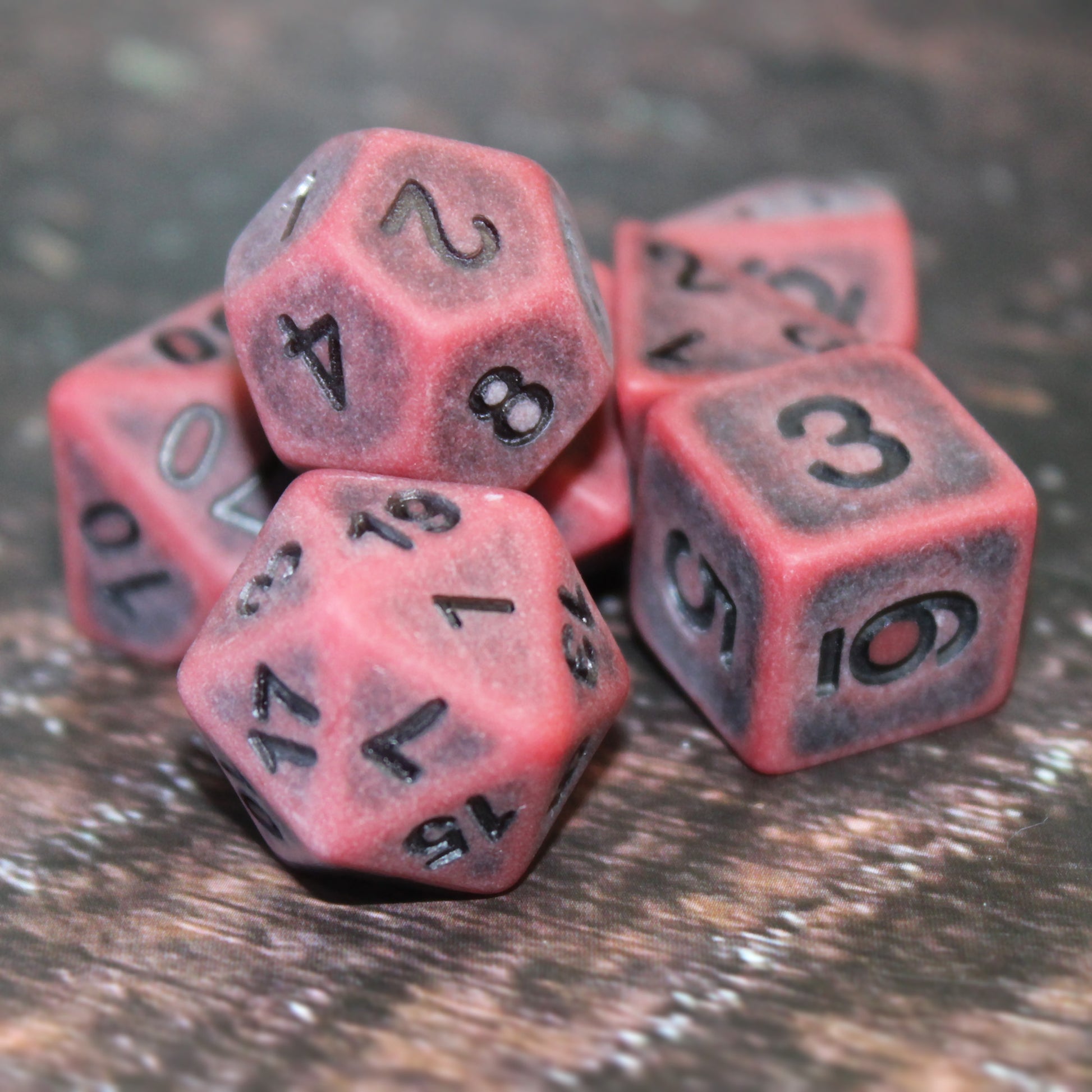 Antiqued red plastic dice with black inked number. The weathering effect makes them see sun bleached and old.