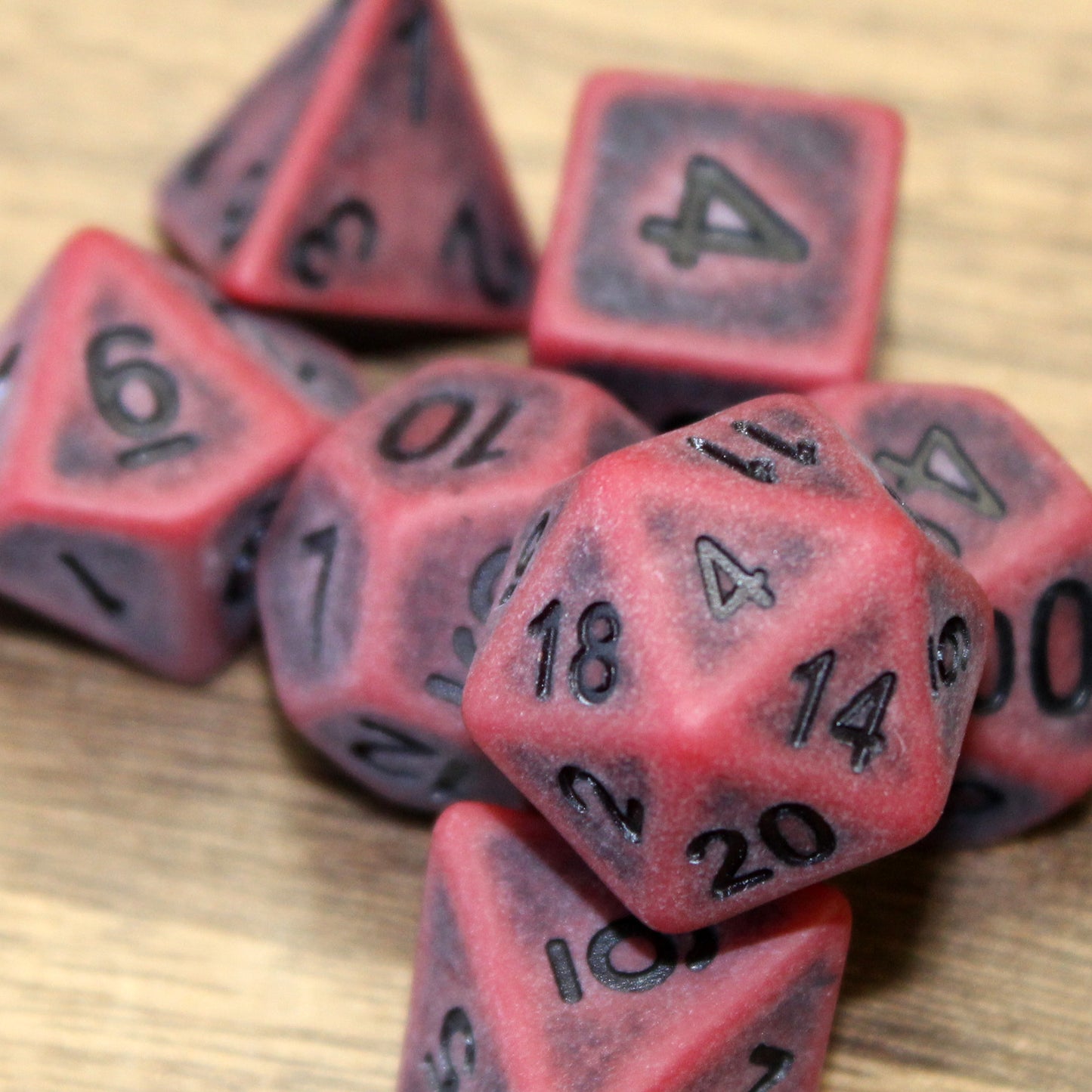 Closup of the d20 of the Ancient Red Polymer Dice Set. The red set is weathered for a antiqued style and inked with black numbers.