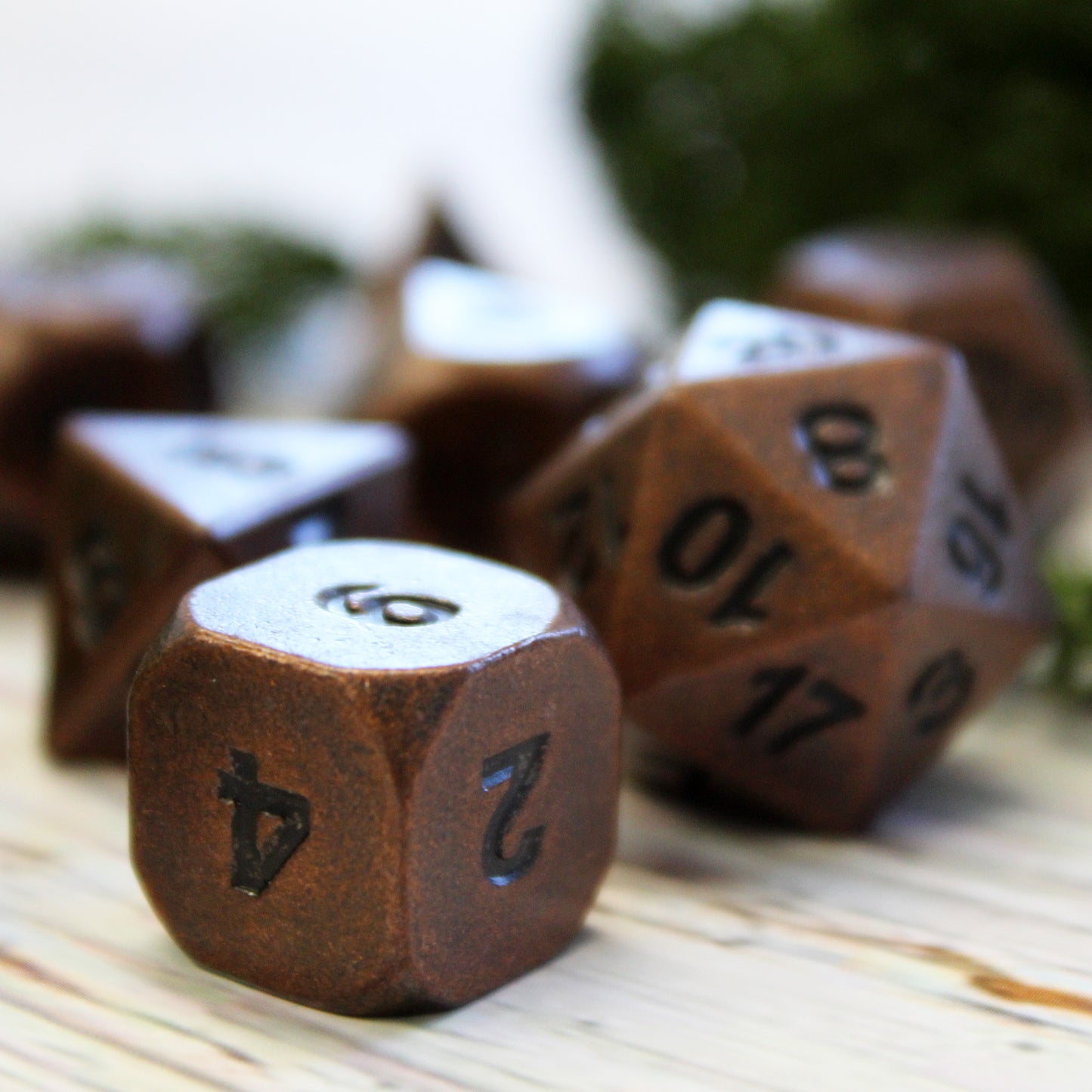 Close-up of Primordial copper dice set on a light wooden surface. The close-up showcases the copper surface and dark numbering.